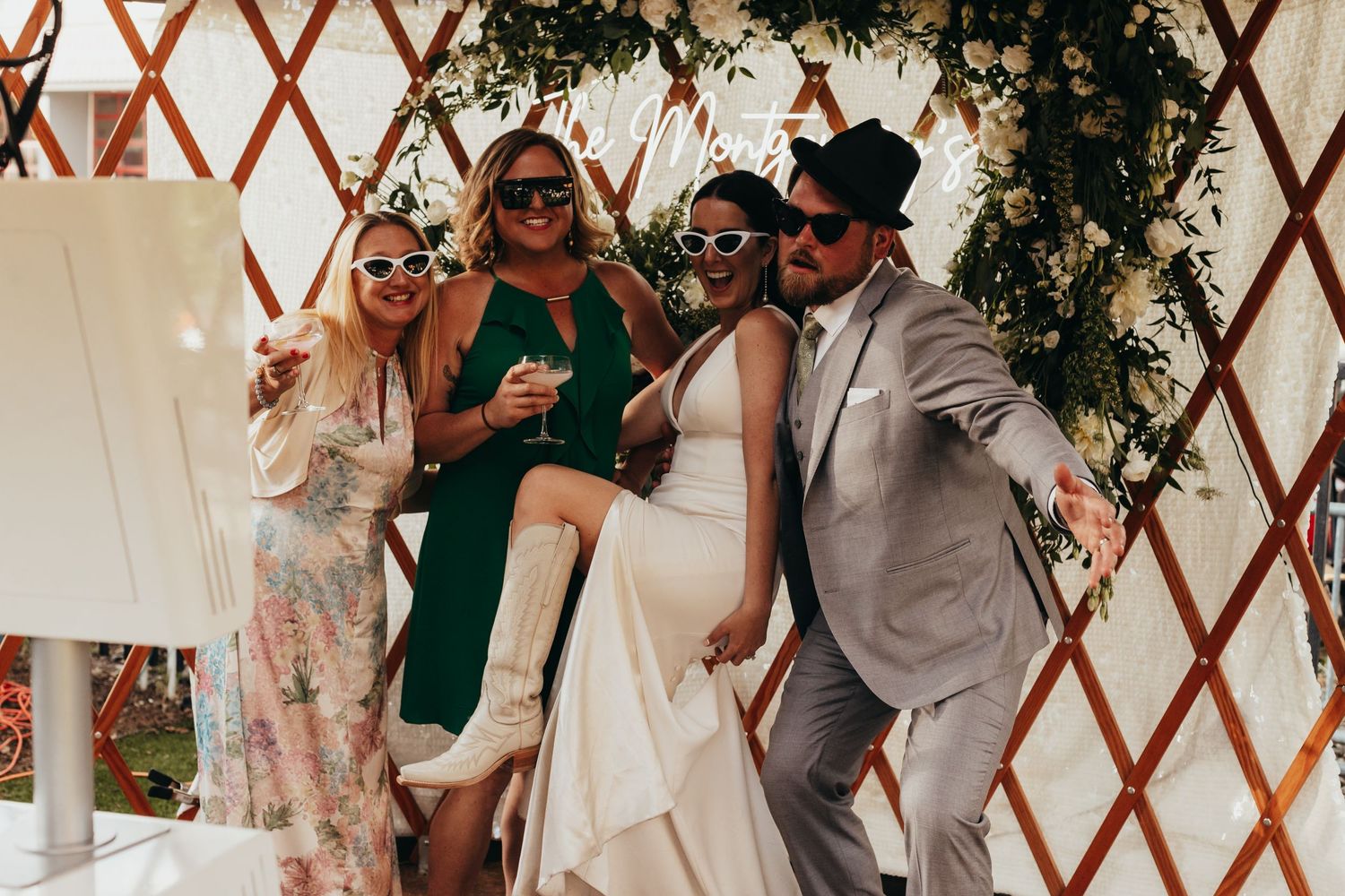 Wedding party posing playfully together in front of decorative yurt structure.