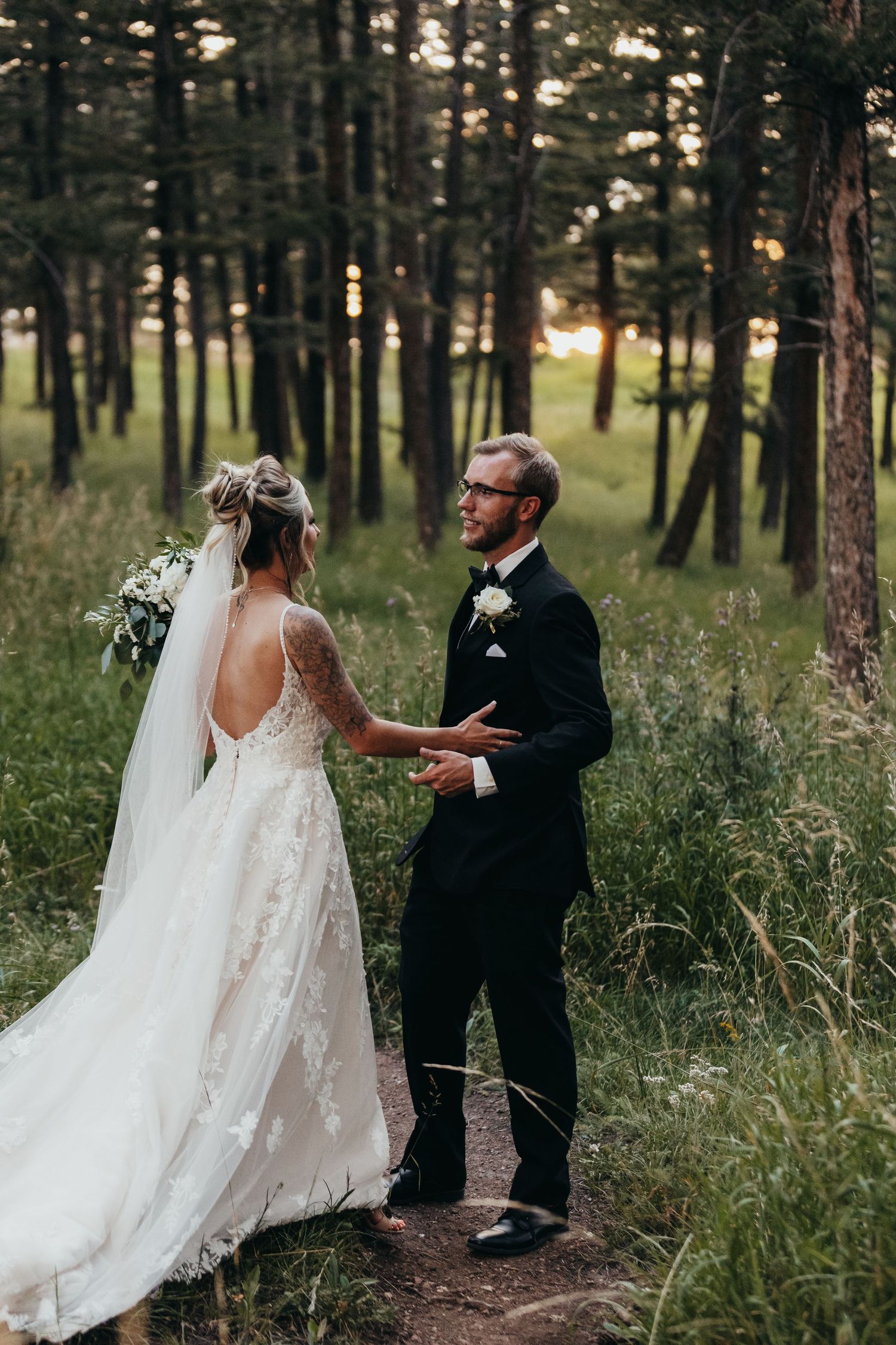 A romantic wedding portrait of a couple in a pine forest with soft natural lighting.