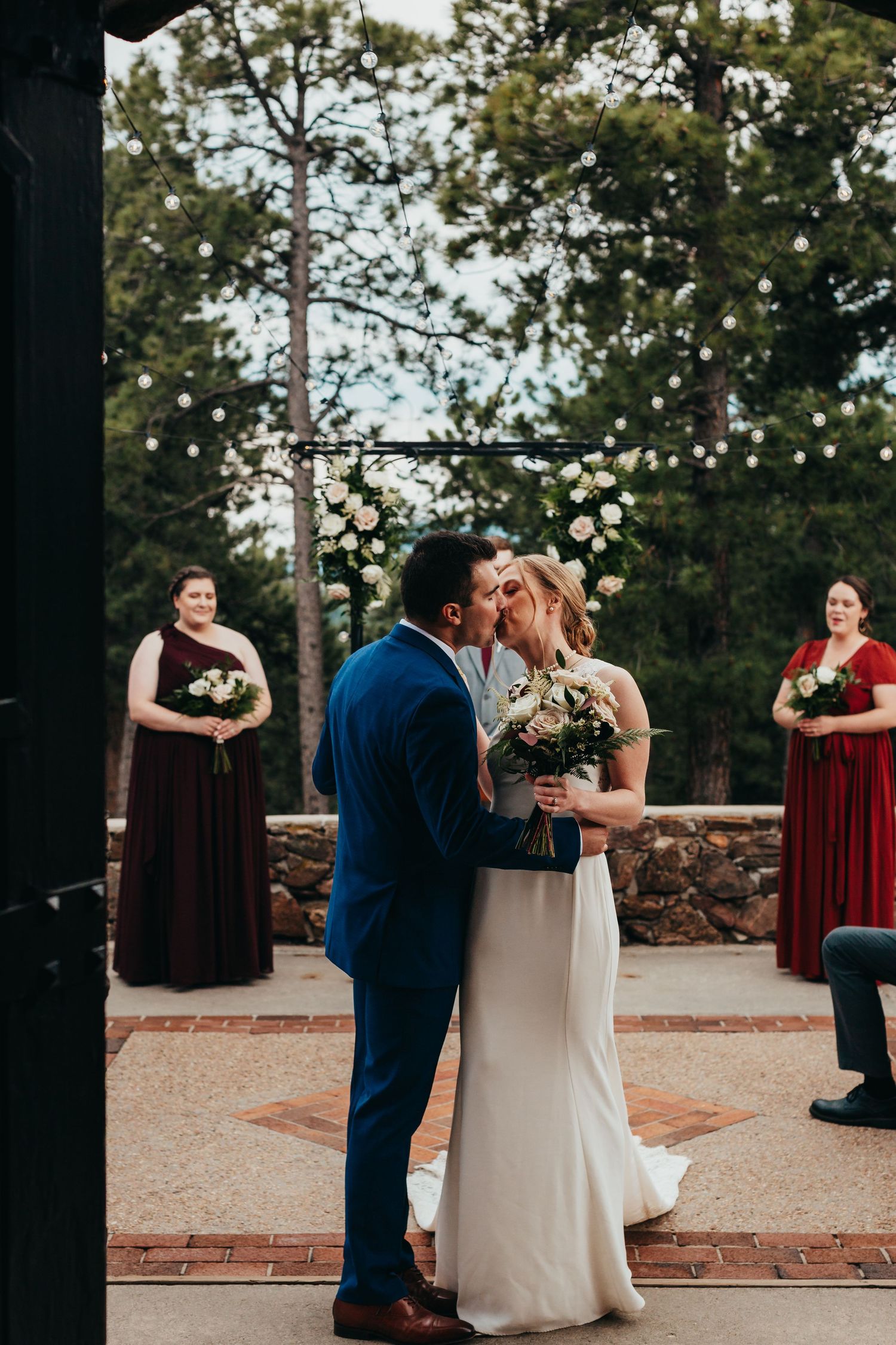 Outdoor wedding ceremony with couple exchanging vows surrounded by burgundy-dressed bridesmaids.