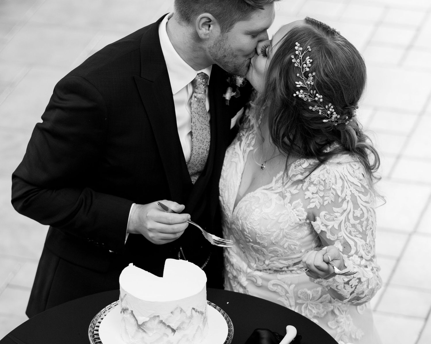 A wedding couple shares a playful moment while cutting their cake together.