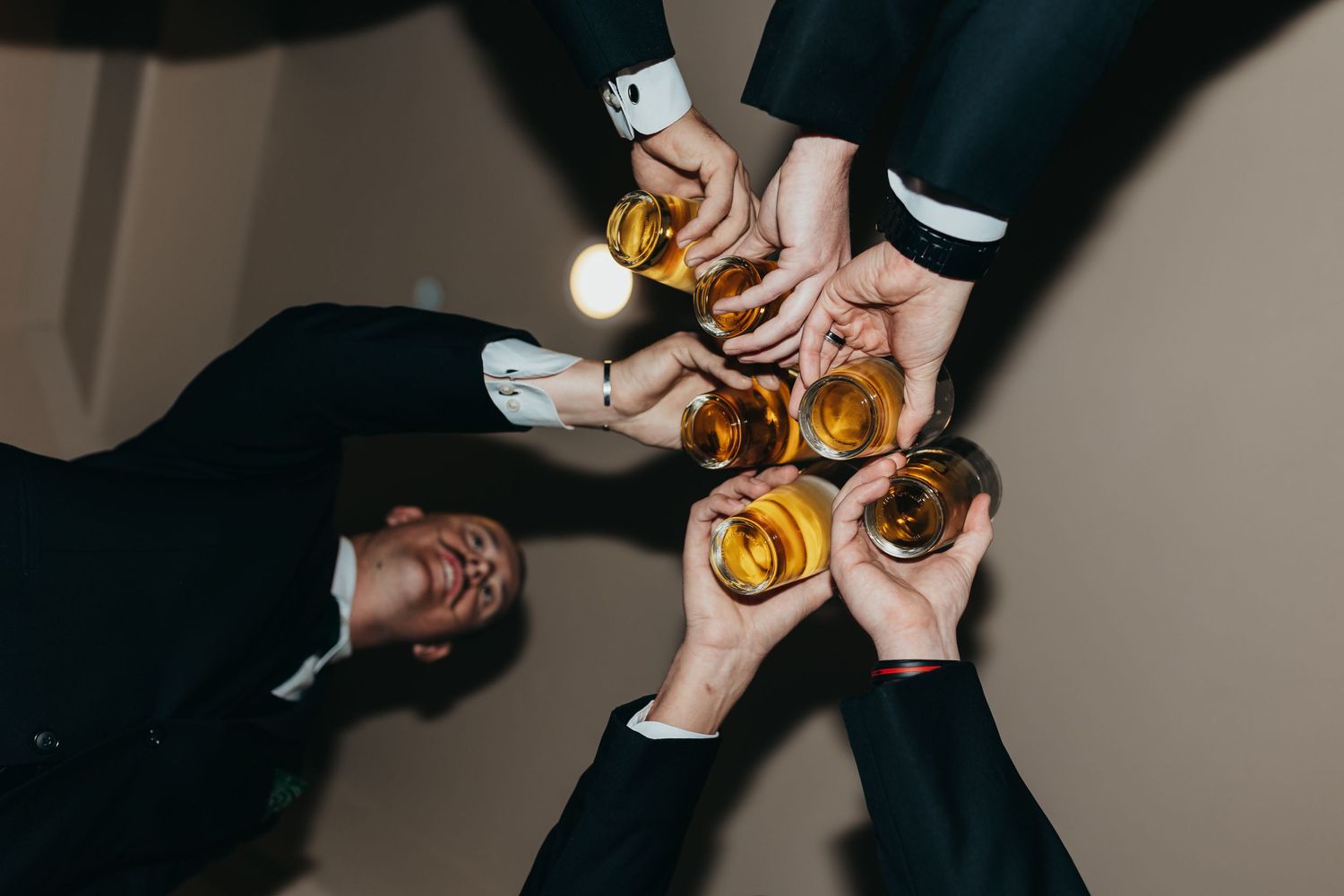 Overhead view of hands toasting with whiskey glasses.