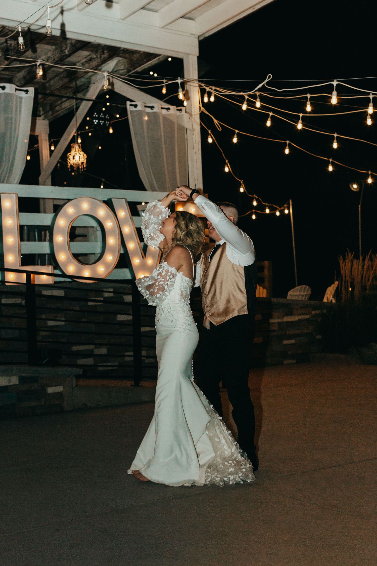 Romantic evening dance scene with illuminated LOVE sign and string lights creating a magical atmosphere.