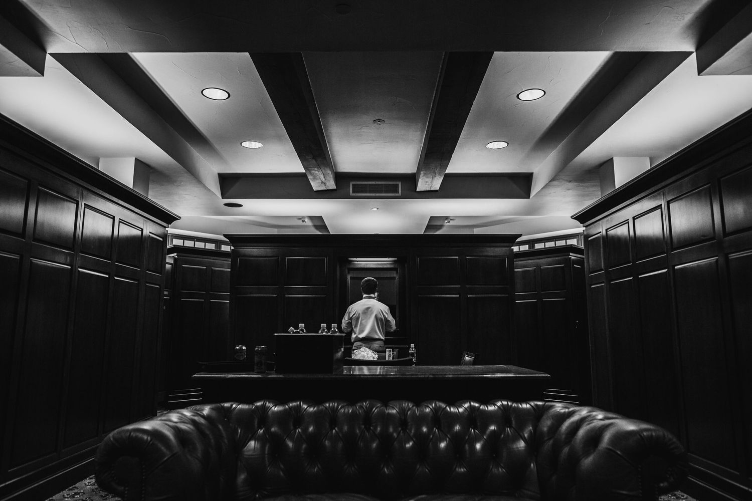 Black and white photo of empty locker room with leather couch and dramatic lighting.