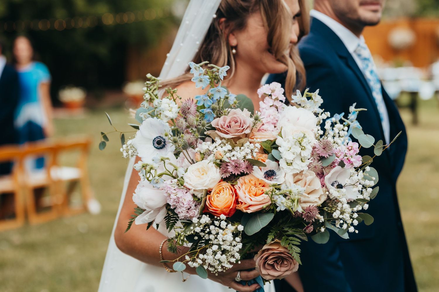 Close-up of romantic pastel wedding bouquet with roses, anemones and baby's breath.