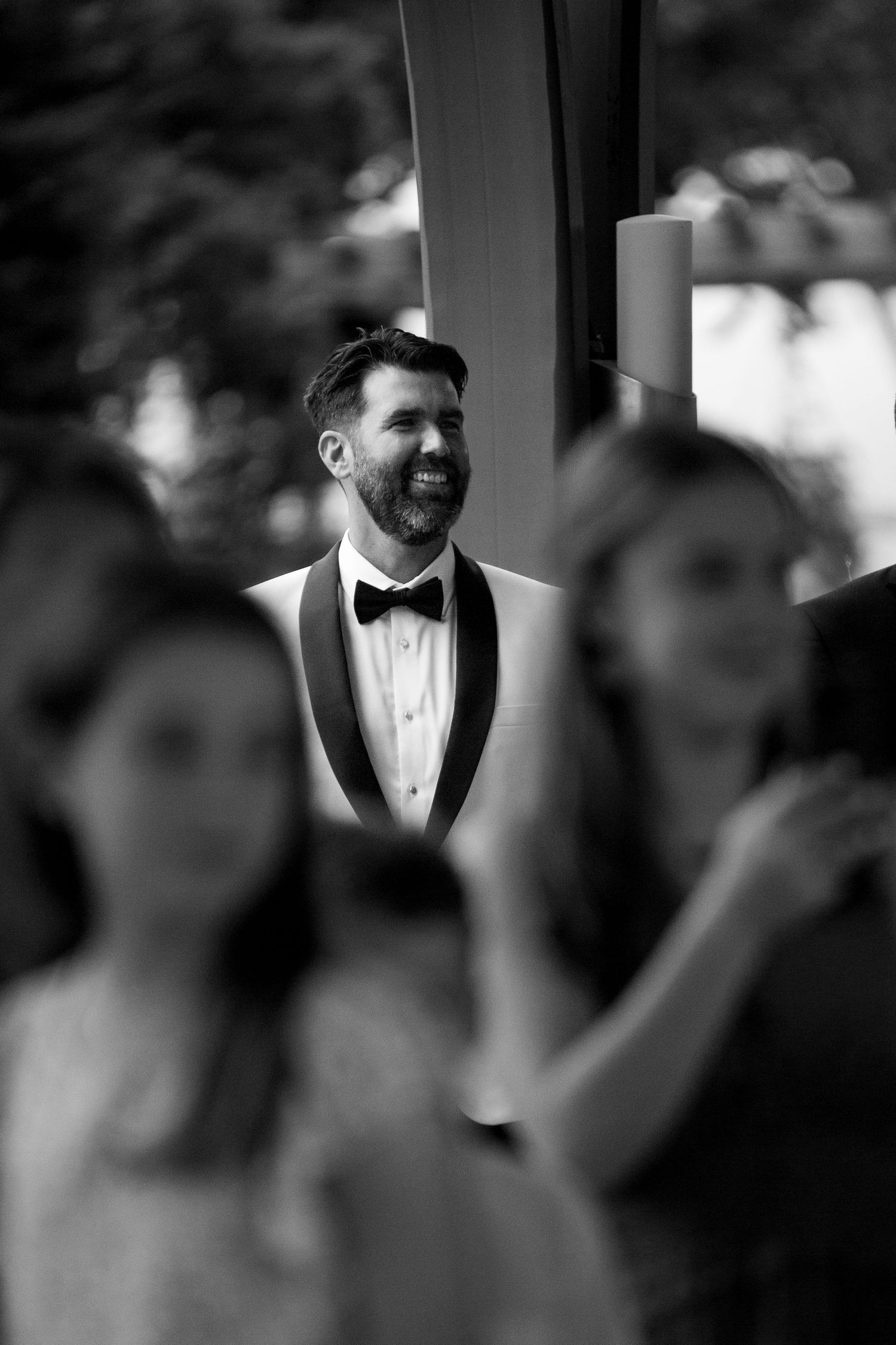 Black and white portrait of groom in tuxedo during wedding ceremony.