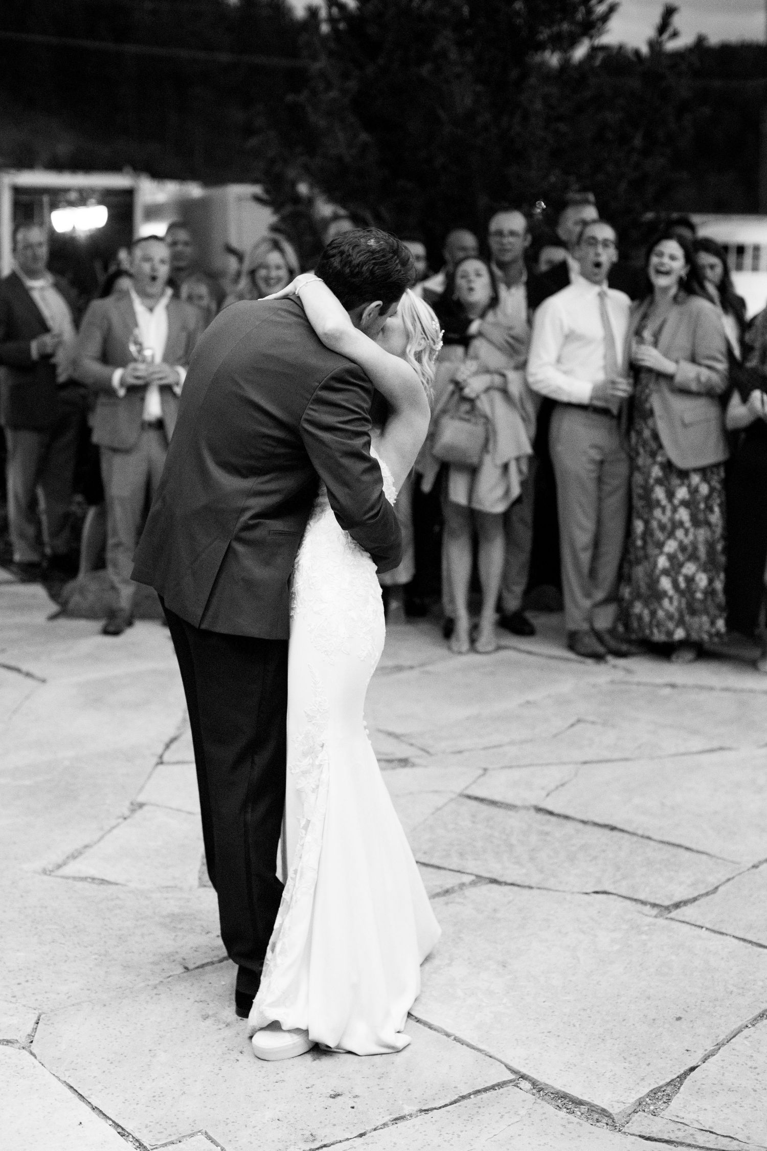 Black and white photo of a romantic first dance at an outdoor wedding reception.