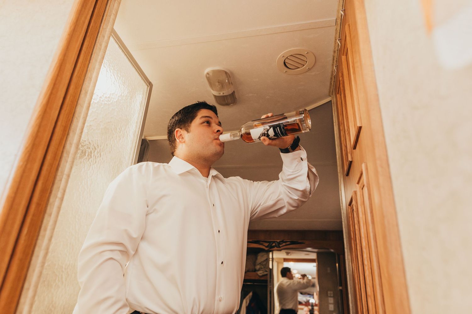 Person in white shirt installing light fixture in narrow hallway.