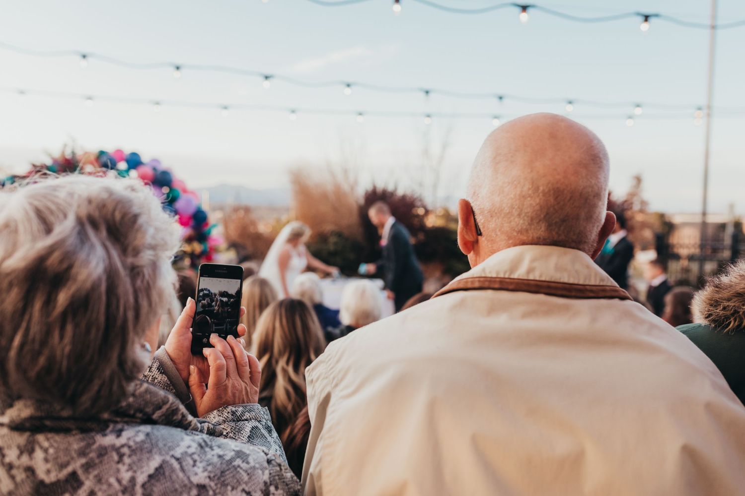 Crowd of people taking photos at an outdoor event with phones raised.