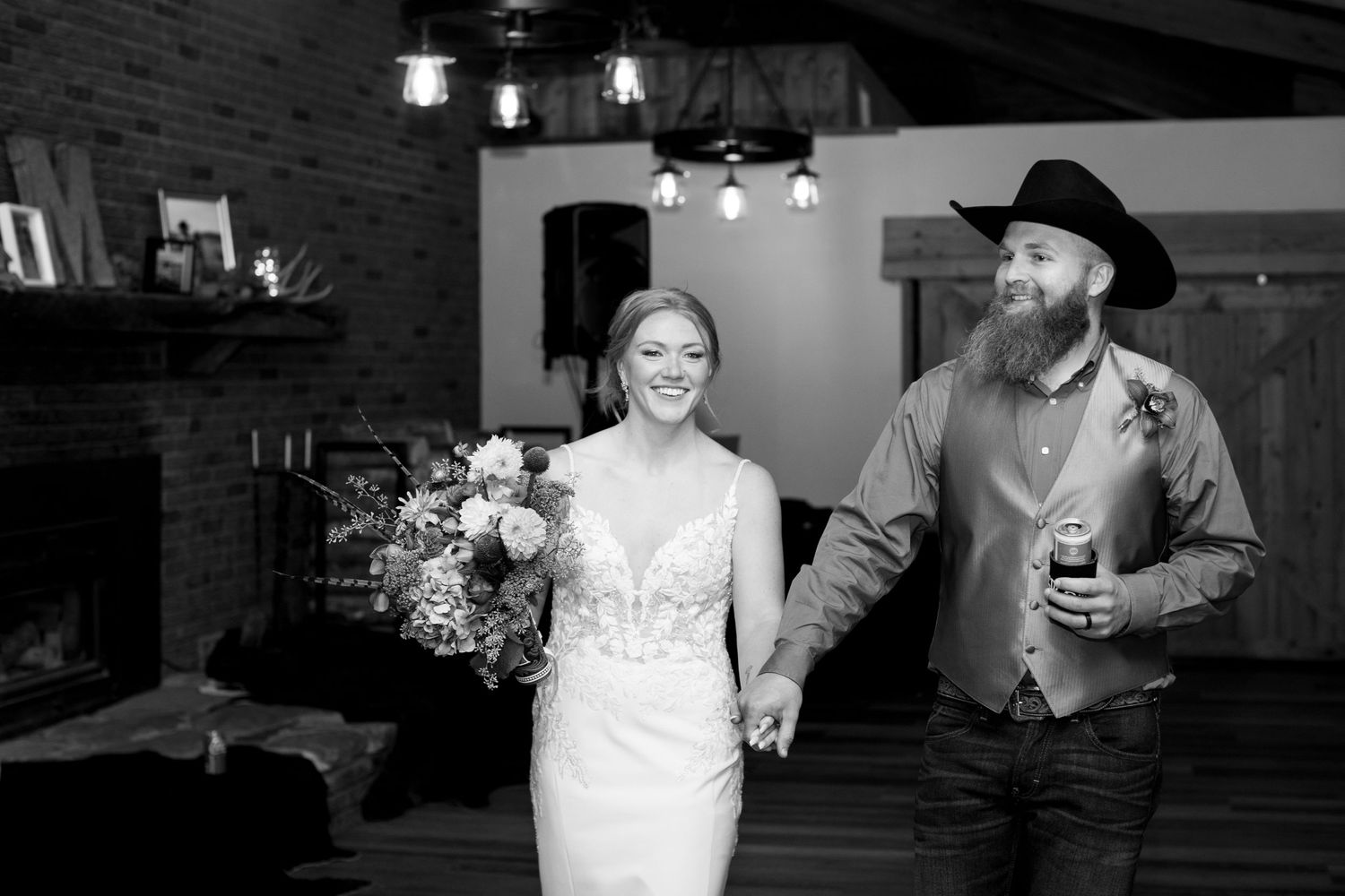 A couple celebrating in a rustic indoor venue with a stone fireplace.