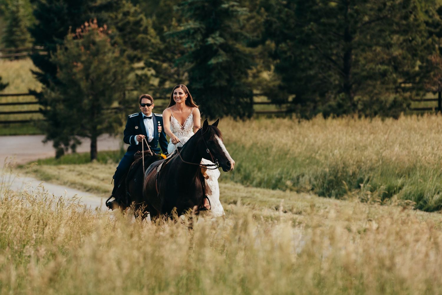 Two riders on horseback traverse a scenic mountain trail during wedding celebration.