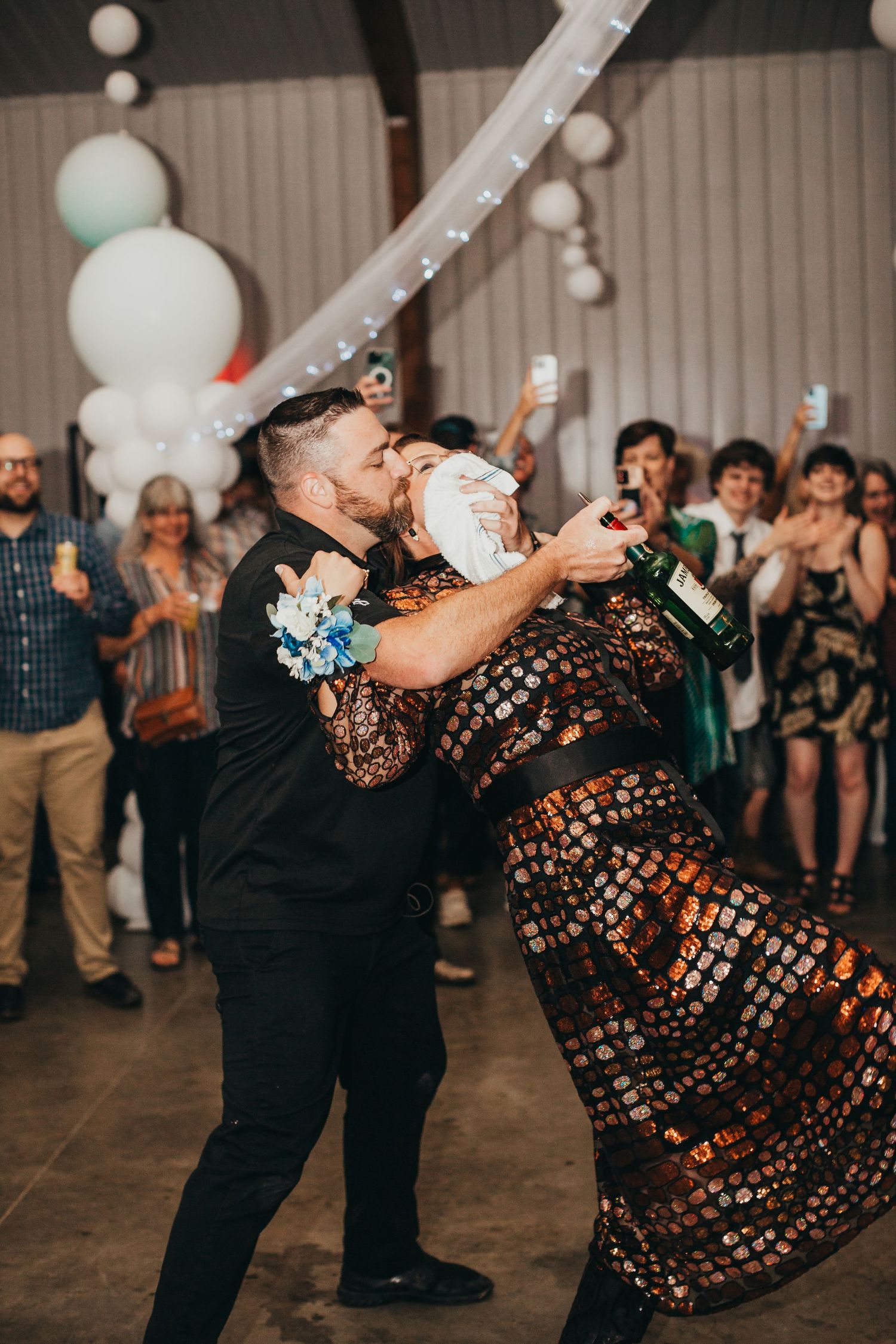 Couple performs dramatic dance move during wedding reception under decorative lighting.