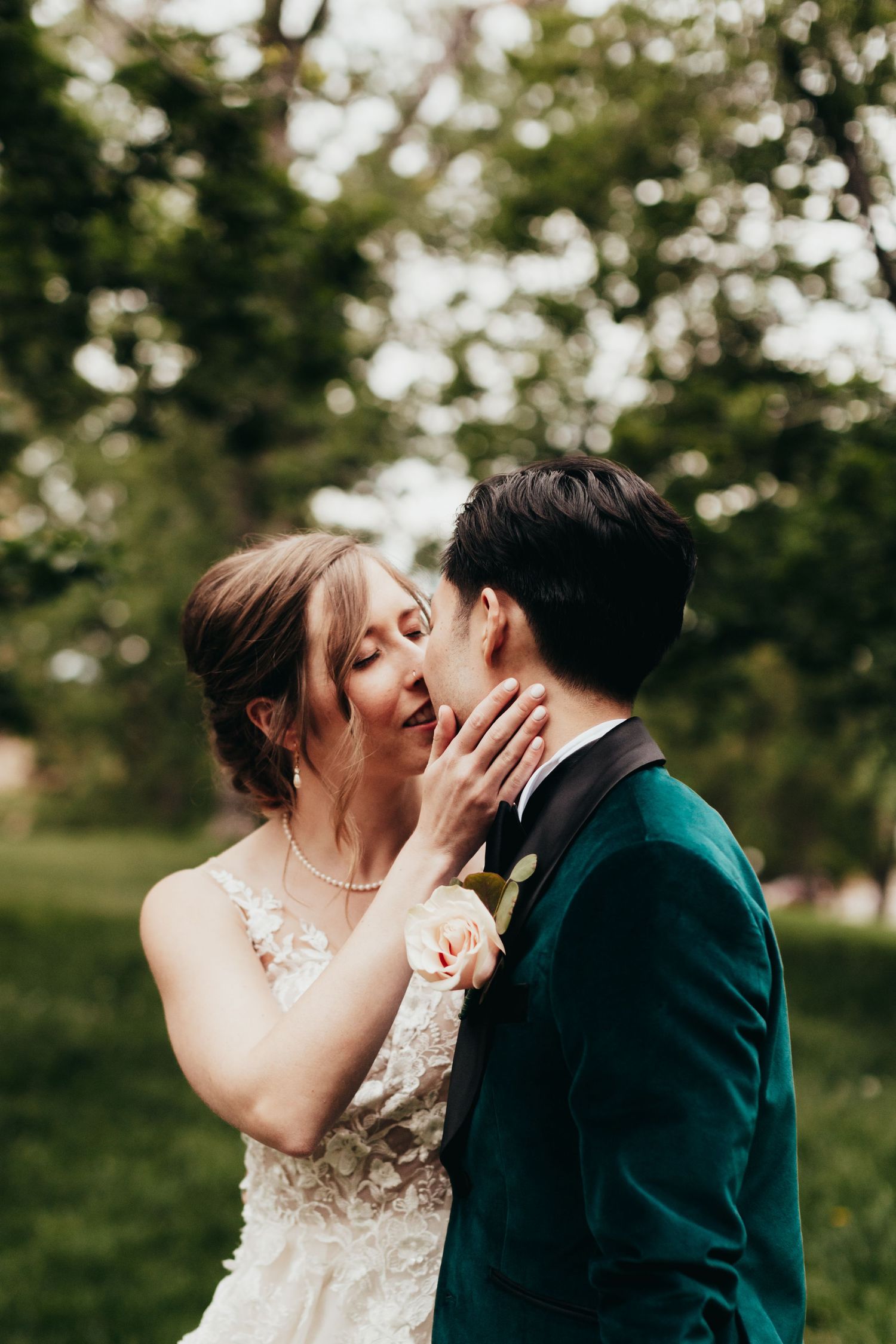 An intimate wedding moment captured outdoors with green foliage in the background.
