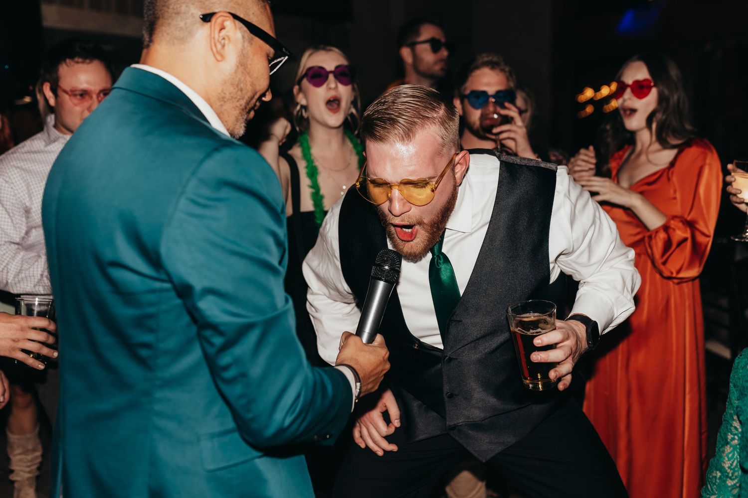 Energetic dance party scene with guests in formal attire enjoying drinks and music.
