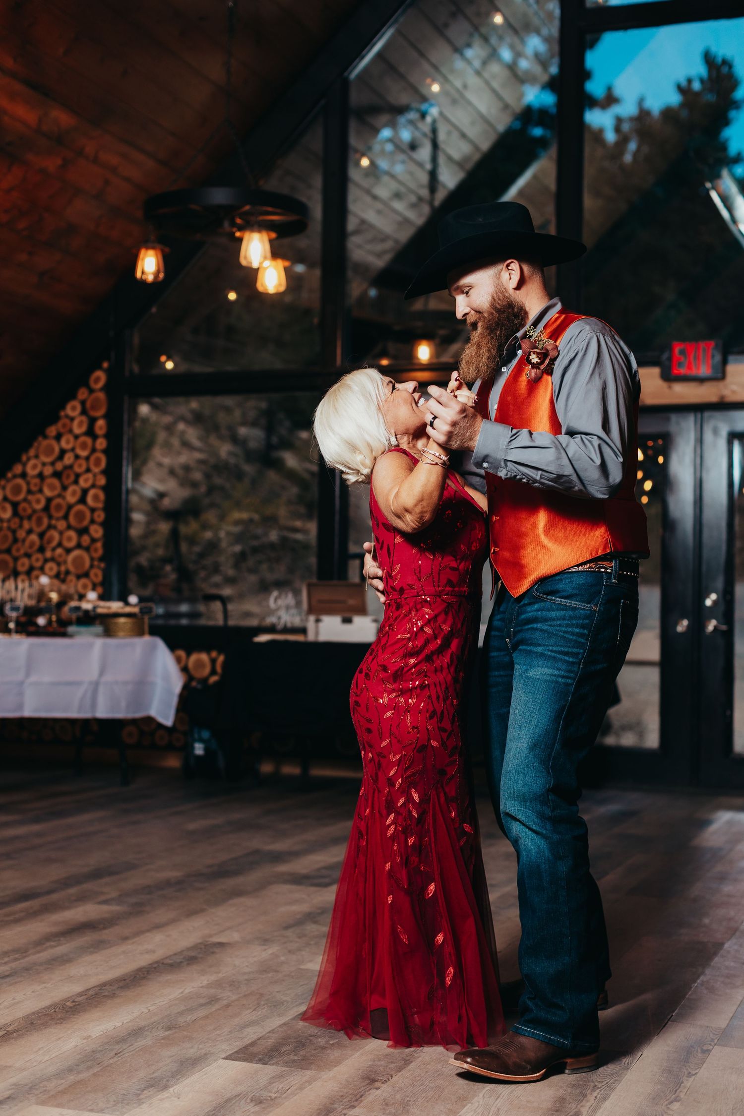 A couple dancing in a rustic venue with wood walls and warm lighting.