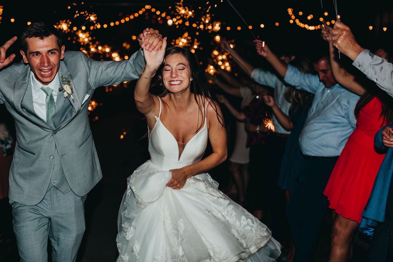 Photo of bride and groom running through a sparkler exit