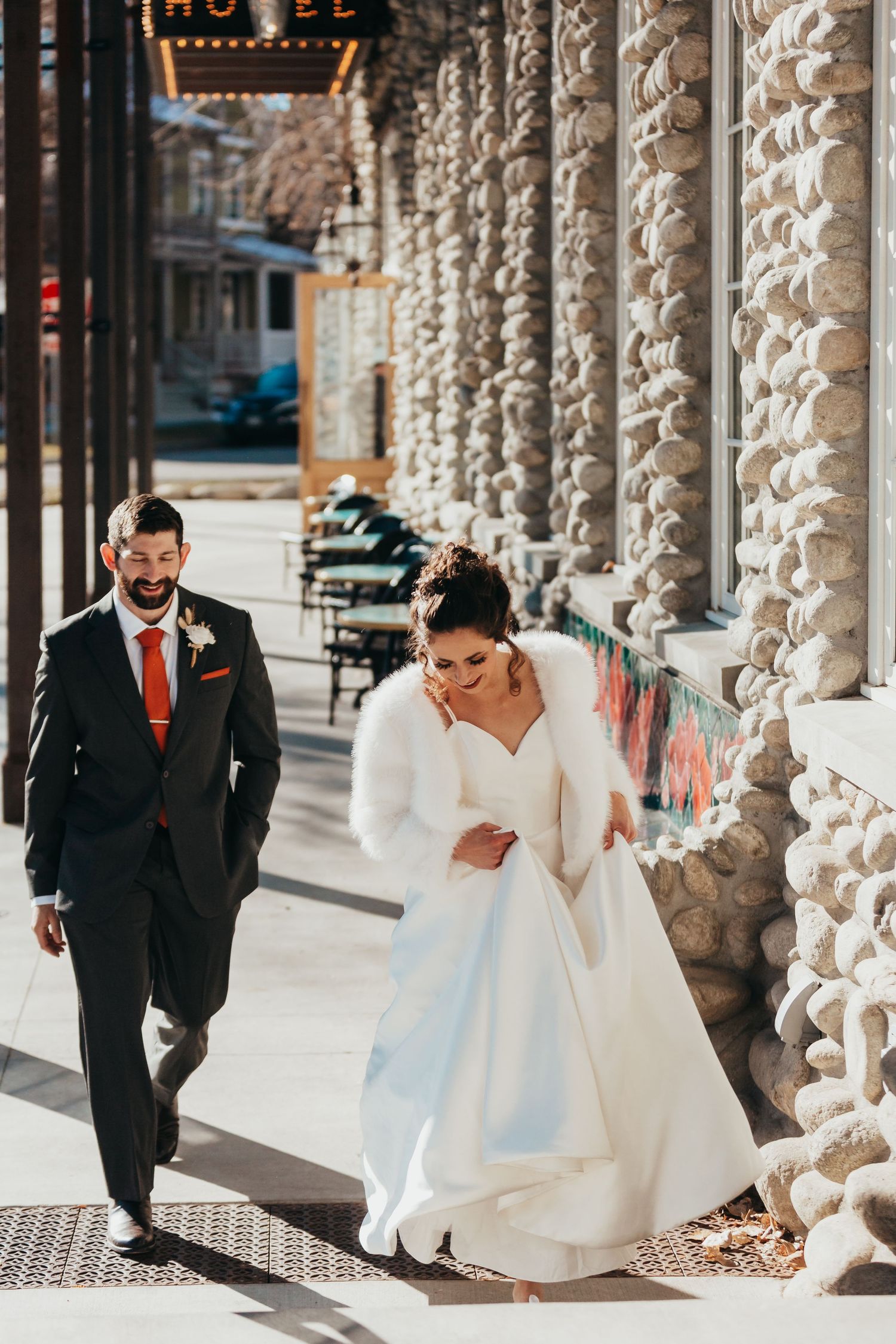 Couple walks along historic columned building facade.