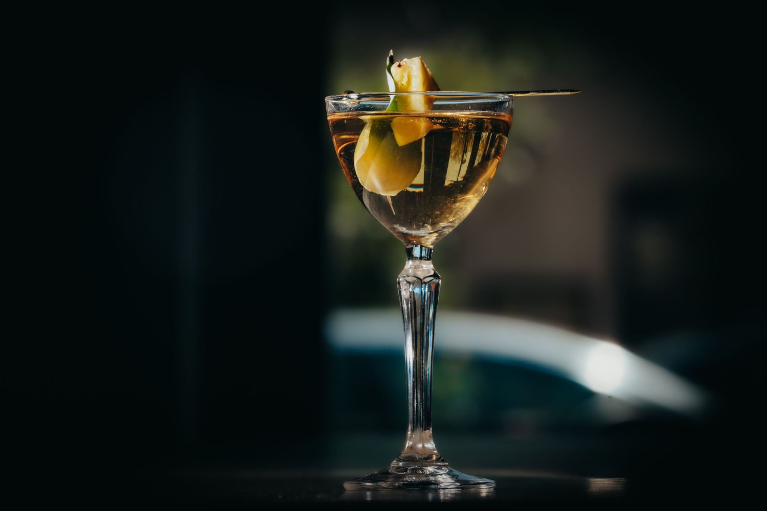 An elegant martini glass filled with golden liquid and garnished with a citrus twist.