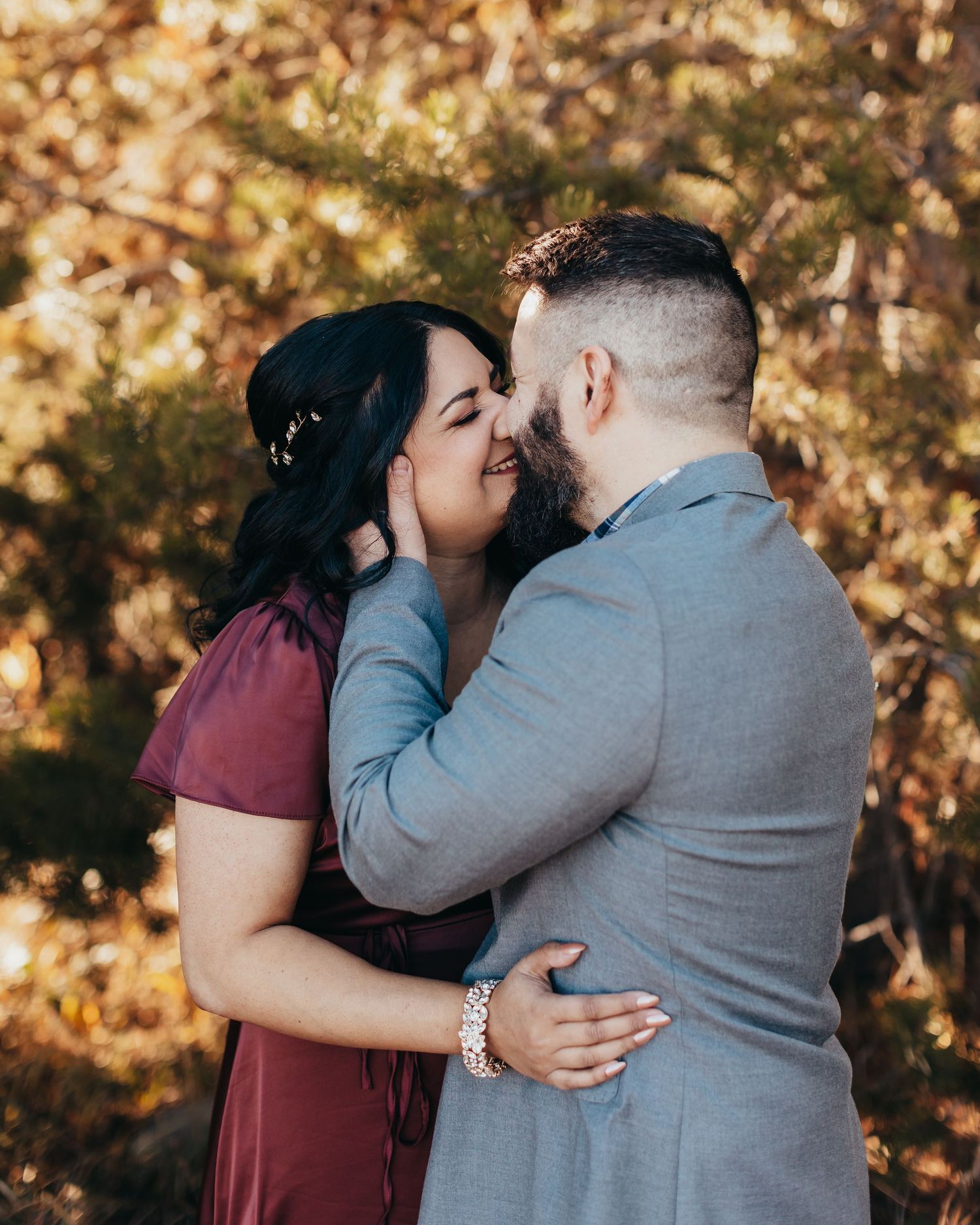 Couple shares intimate moment during autumn photoshoot with golden leaves in background.