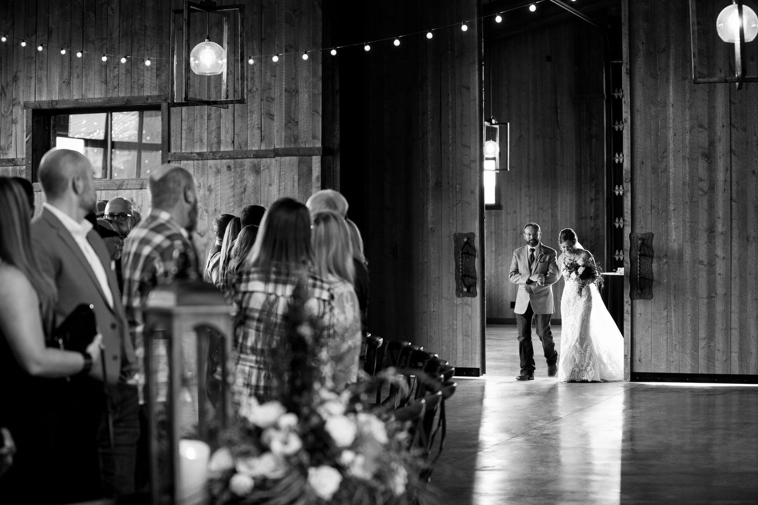 Black and white wedding ceremony photo showing guests watching the entrance procession.