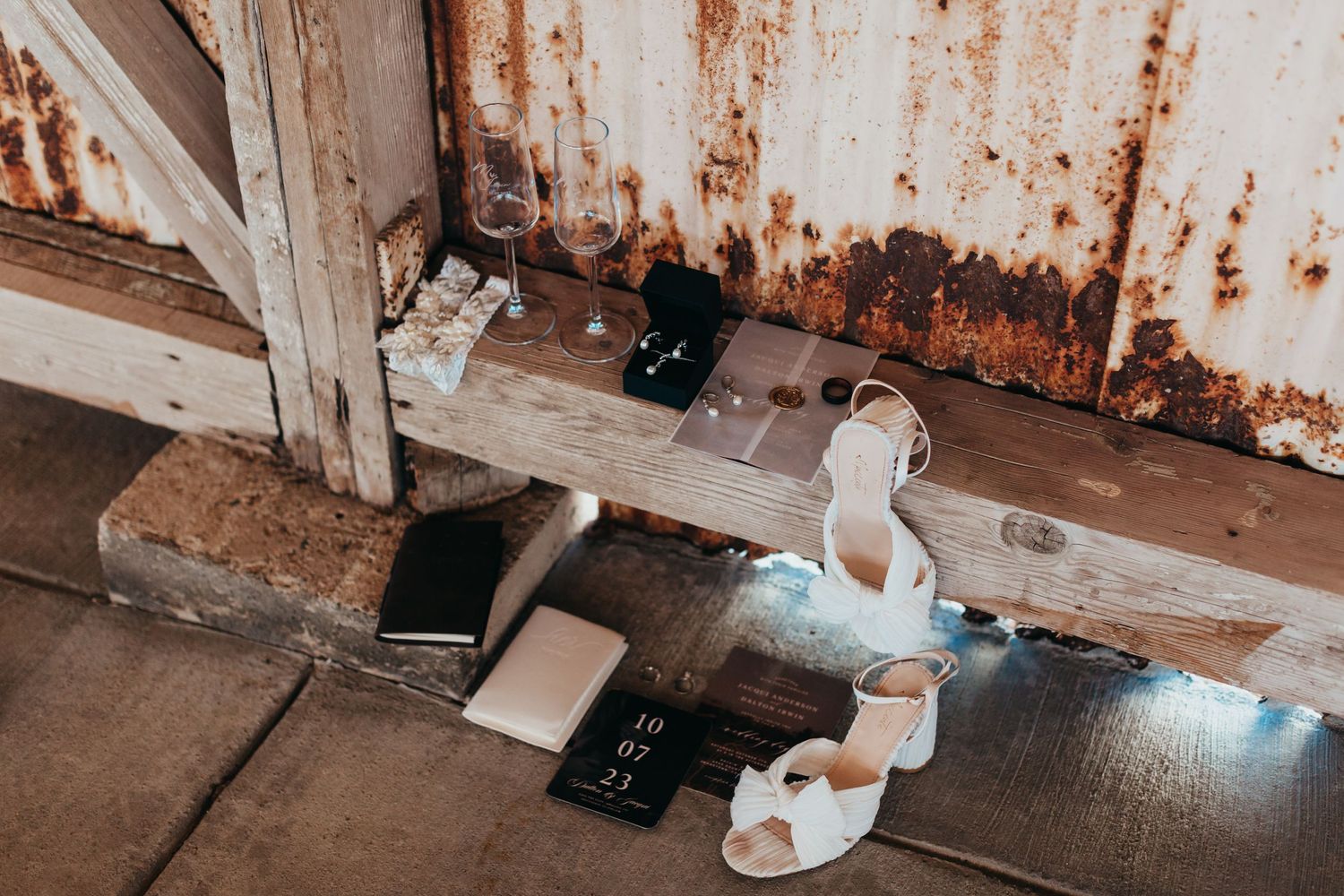 Wedding shoes and accessories arranged on a rustic wooden surface.