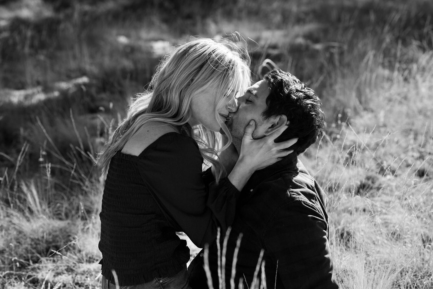 Black and white romantic portrait of couple embracing in a field.