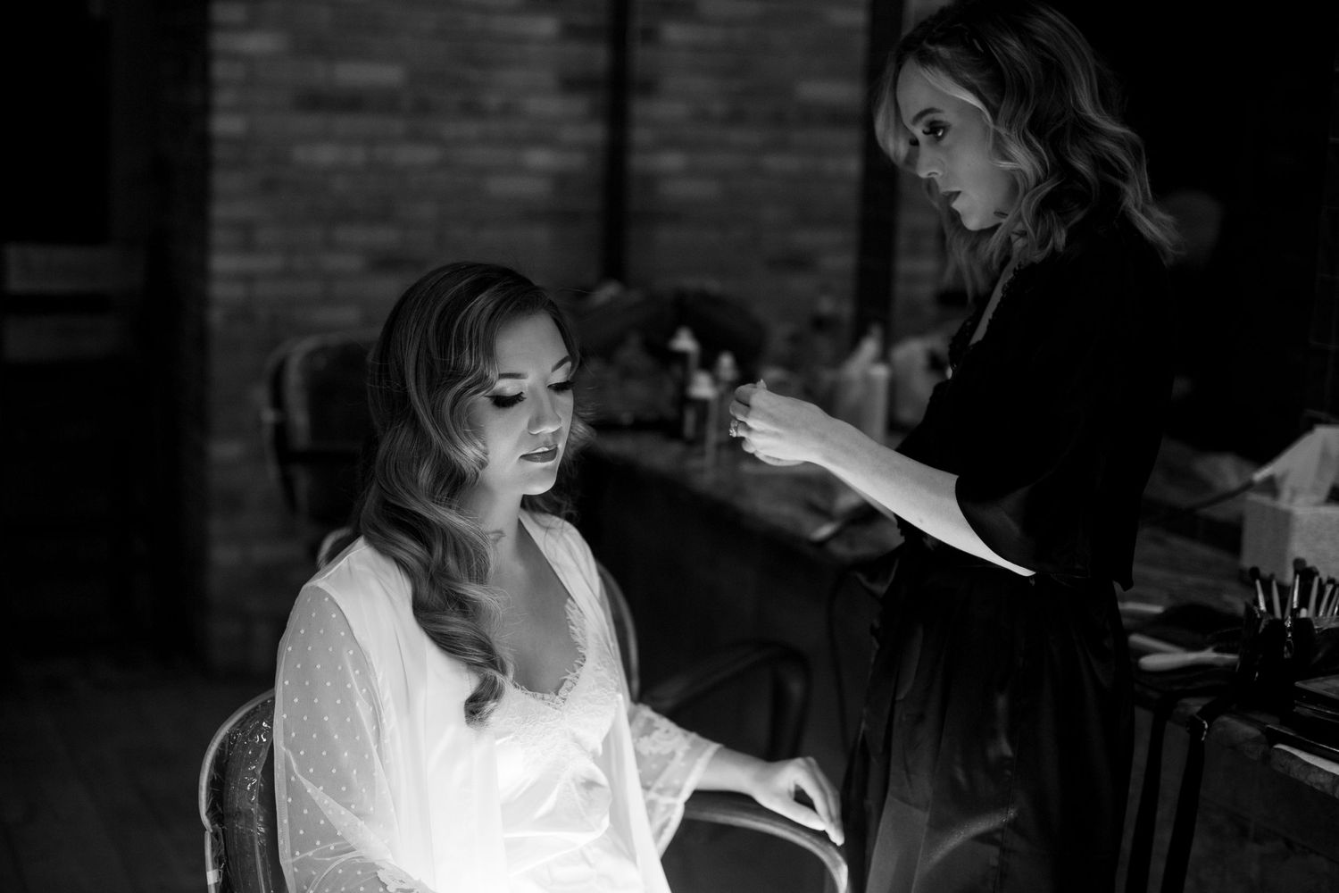Black and white image showing wedding day preparations in a rustic brick setting.