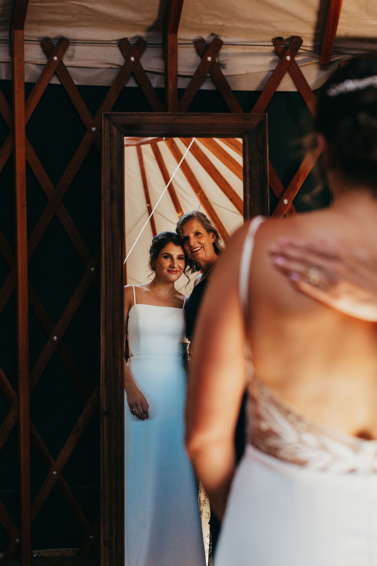 Artistic mirror reflection shot of wedding dress details in a rustic setting.