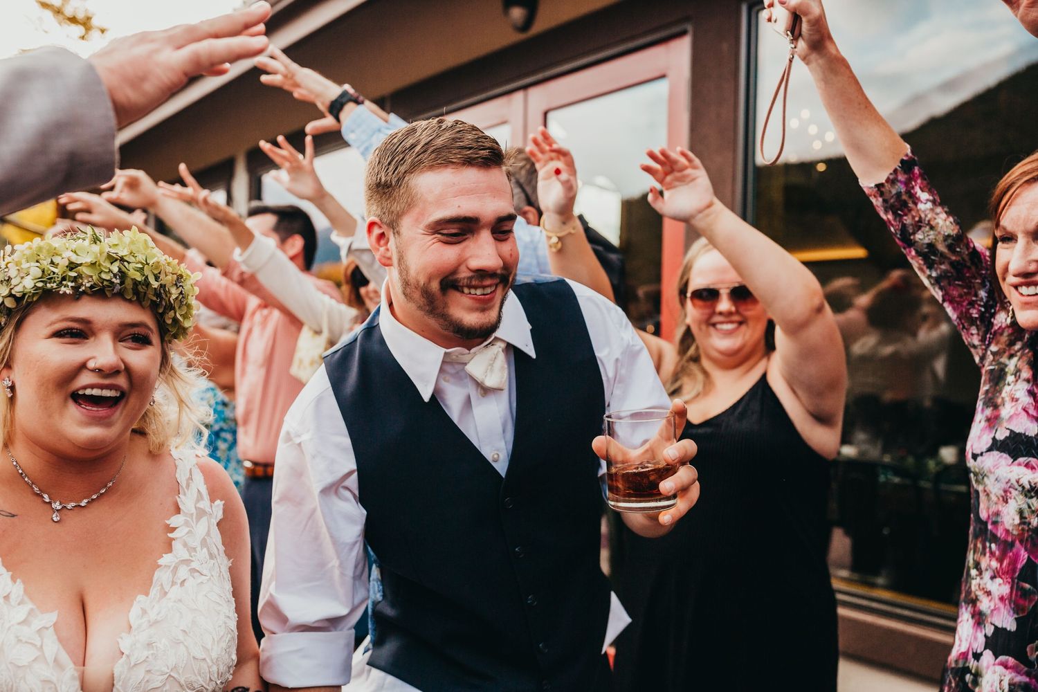 Wedding celebration with guests dancing and celebrating outdoors.