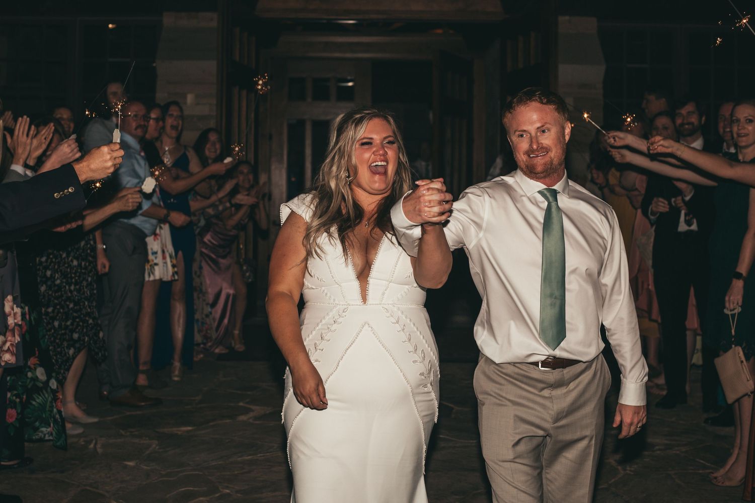 Couple walking through crowd during wedding reception celebration.