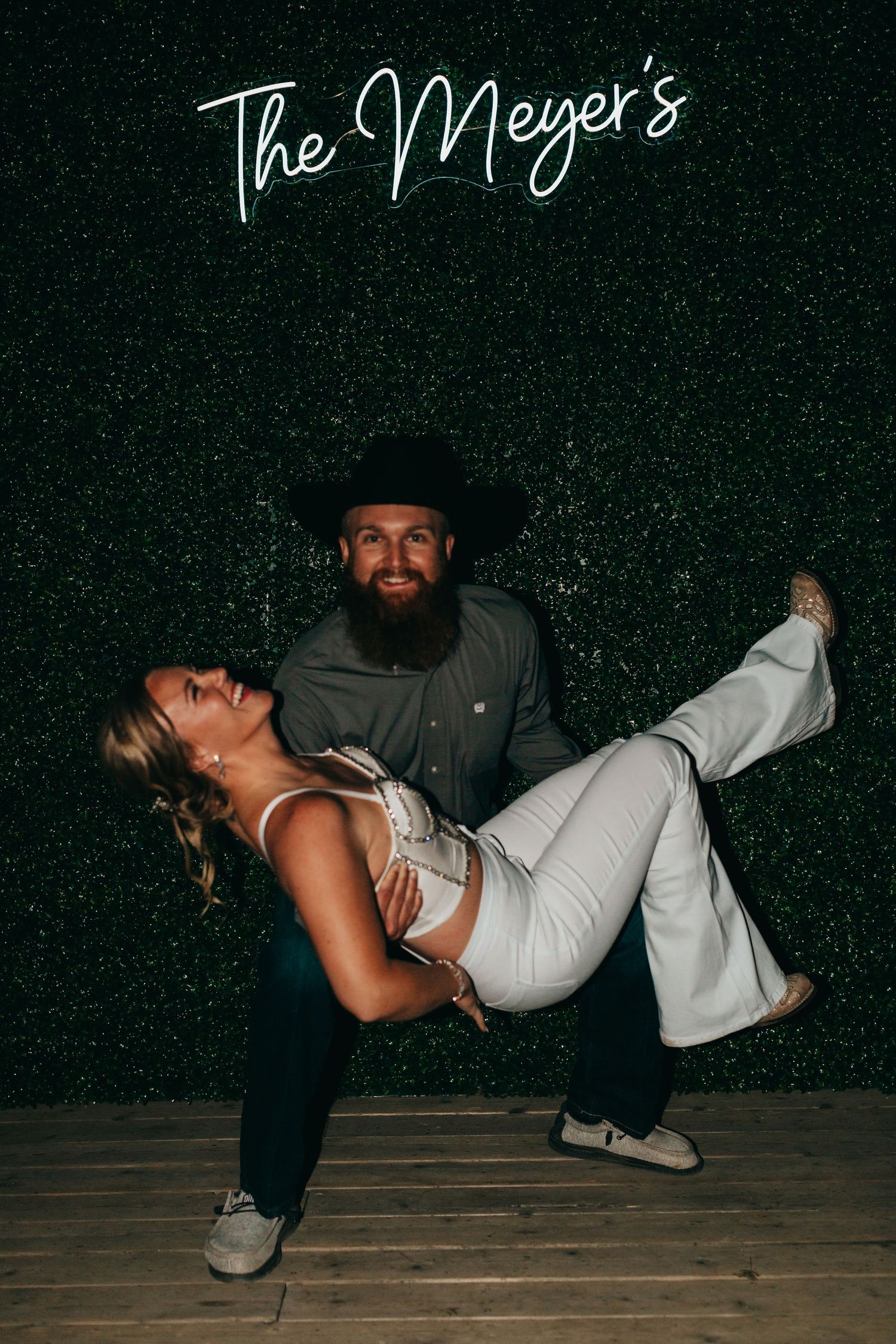 A romantic dip pose in front of a neon 'The Meyer's' sign.
