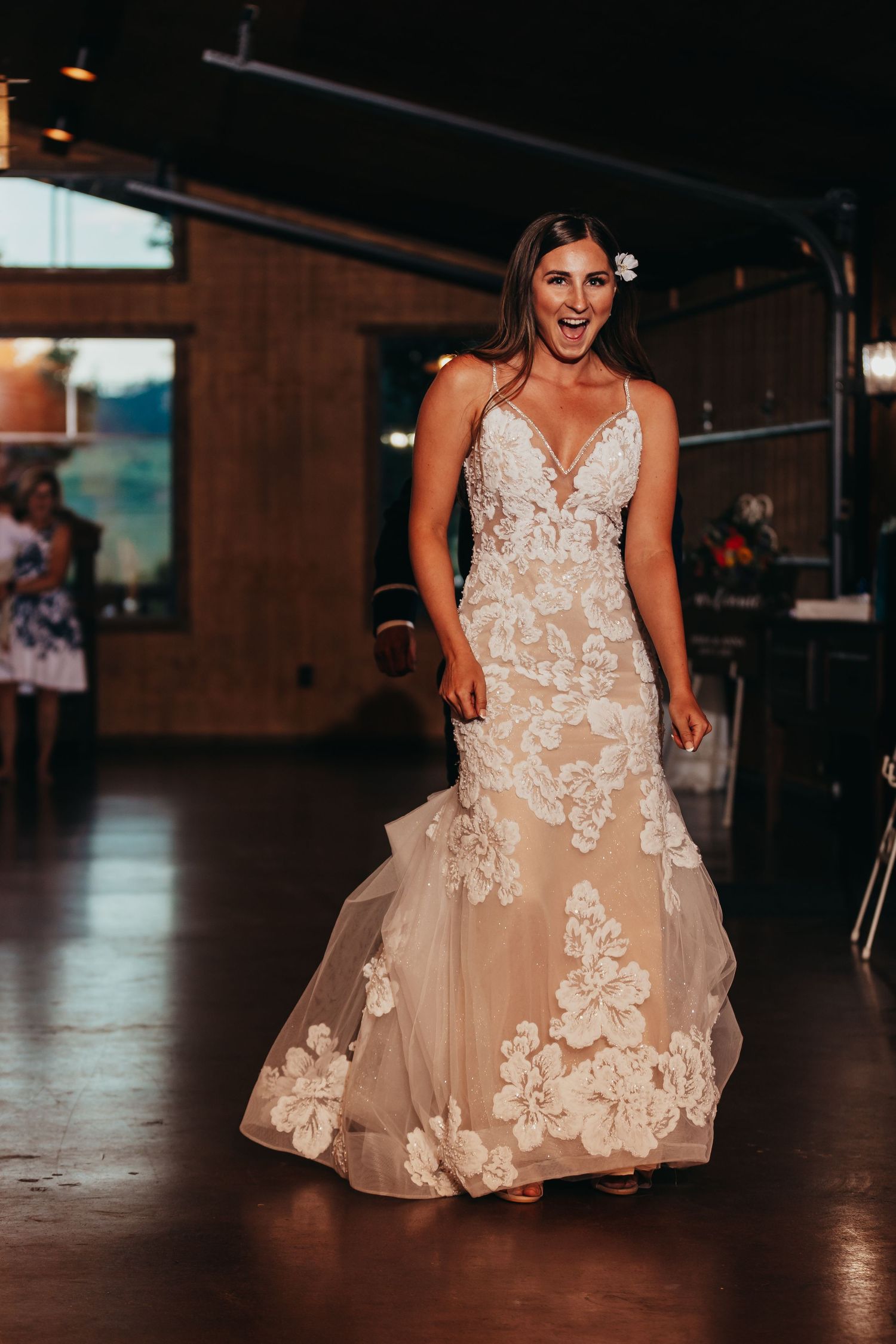 A stunning bride in a lace mermaid wedding gown poses on a rustic wooden floor.