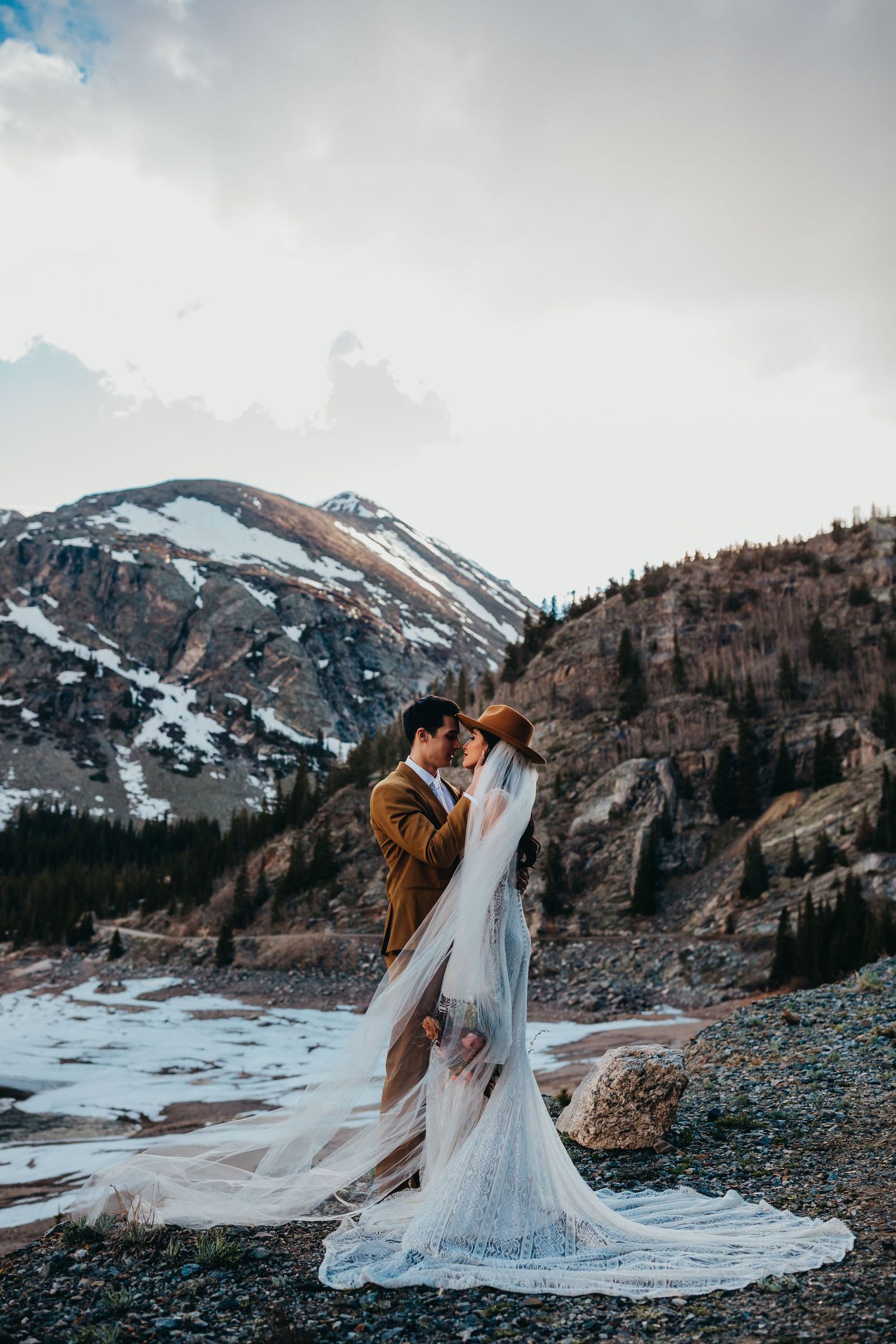 A romantic mountain elopement photo with flowing white dress against rocky terrain.