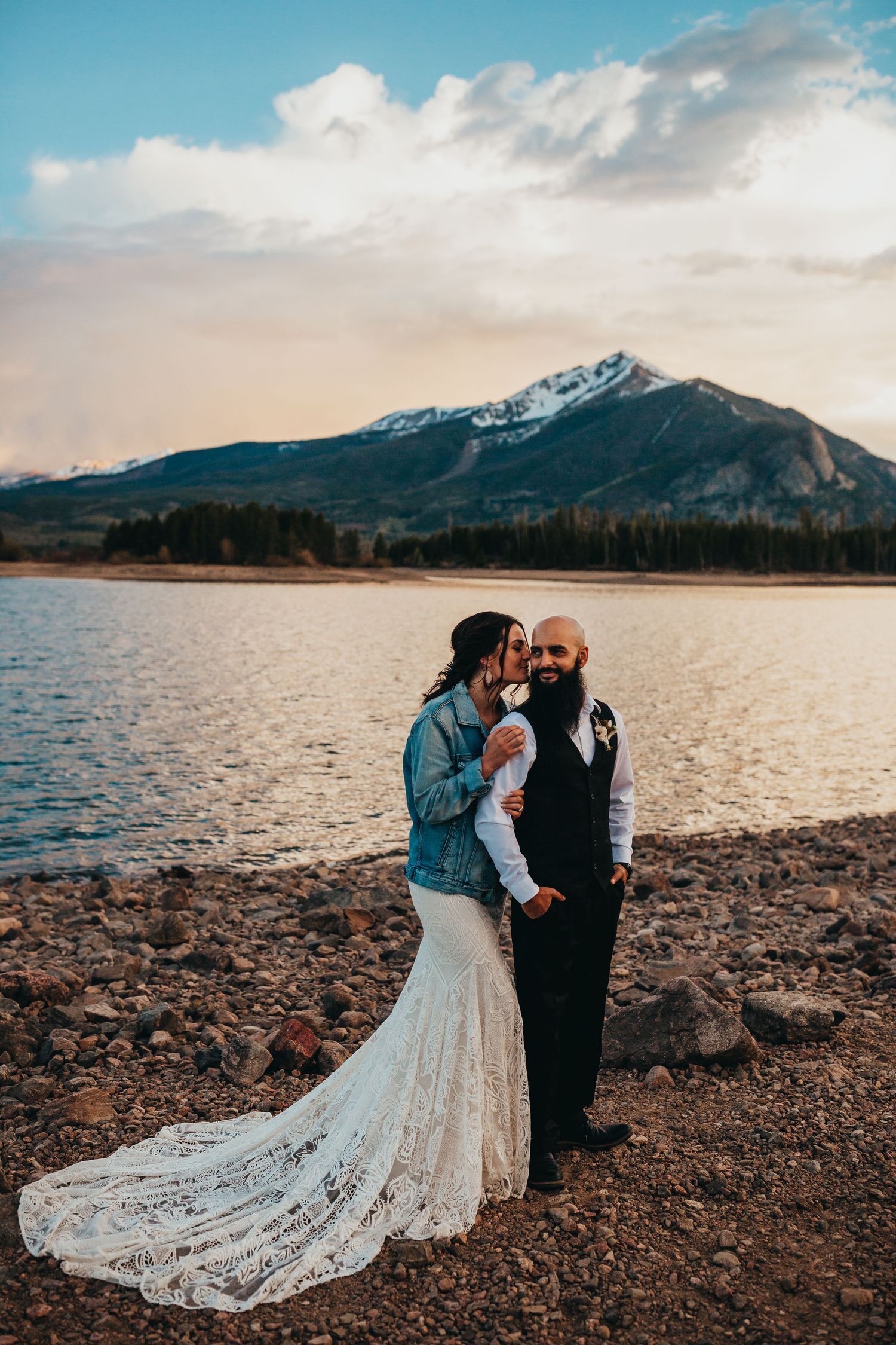 Romantic mountain wedding photography with snow-capped peaks and lake in background.