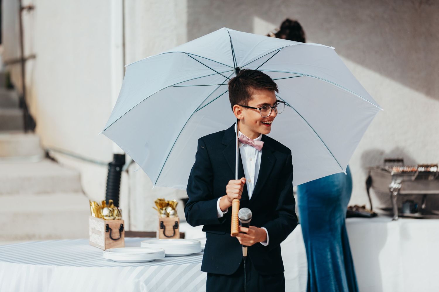 A joyful moment captured with a blue umbrella at an outdoor reception.