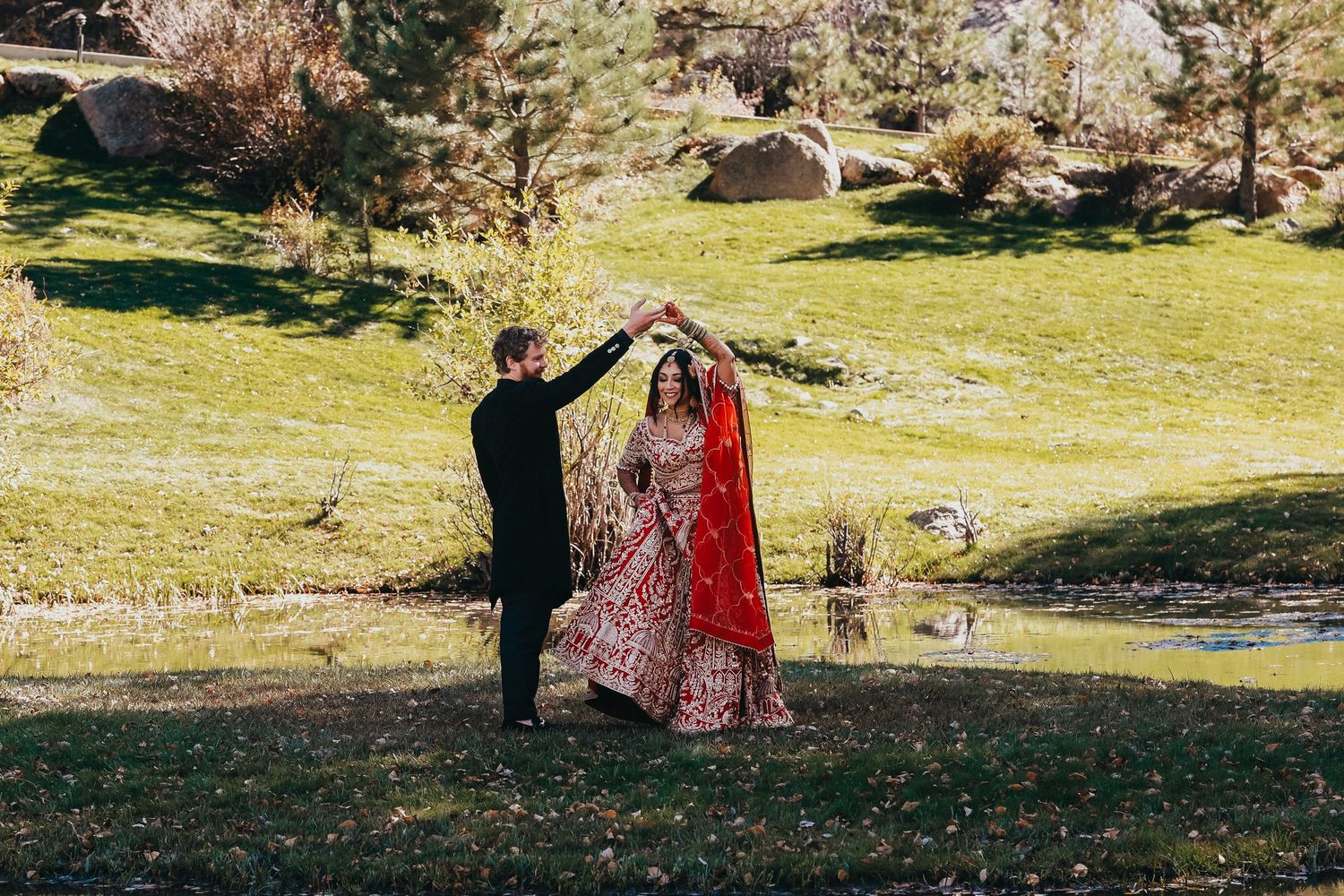 Wedding couple dancing in scenic outdoor setting with mountains and autumn foliage as backdrop.