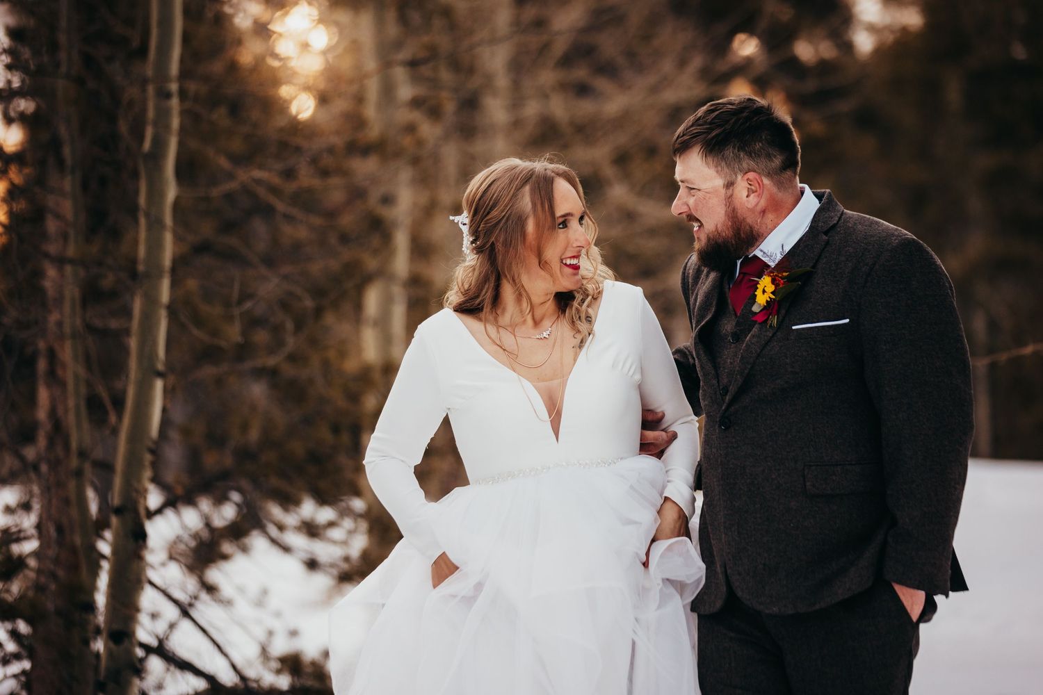 A winter wedding couple shares an intimate moment in a snow-covered forest setting.