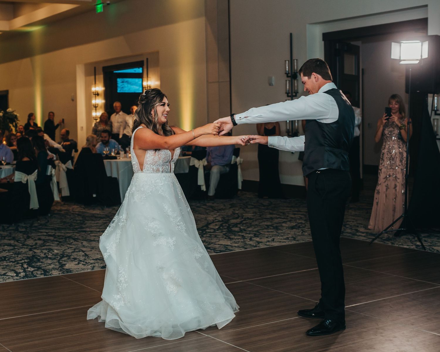 Newlyweds dancing together on the reception dance floor in traditional wedding attire.