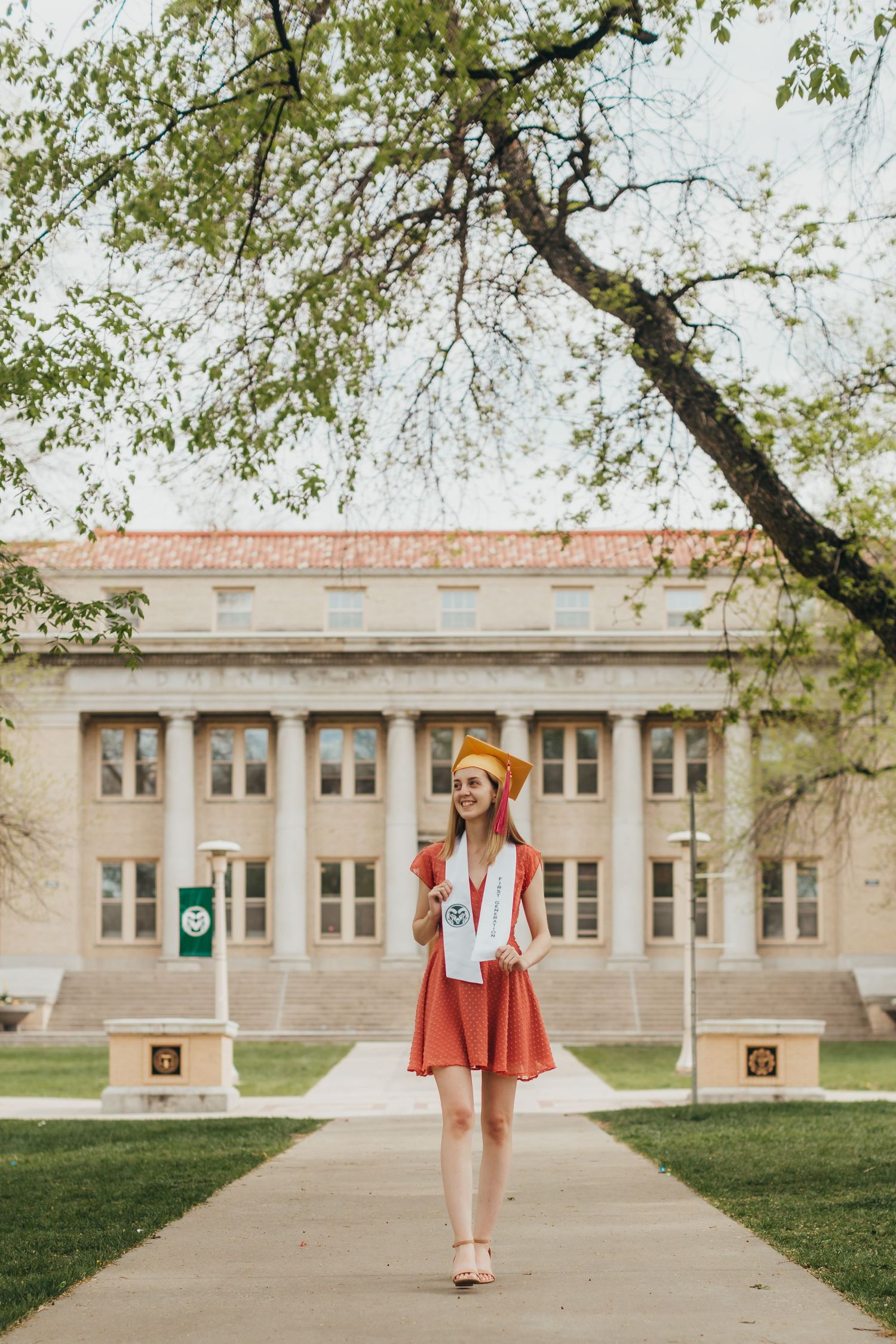 Person in orange beret and skirt standing in front of classic collegiate building.
