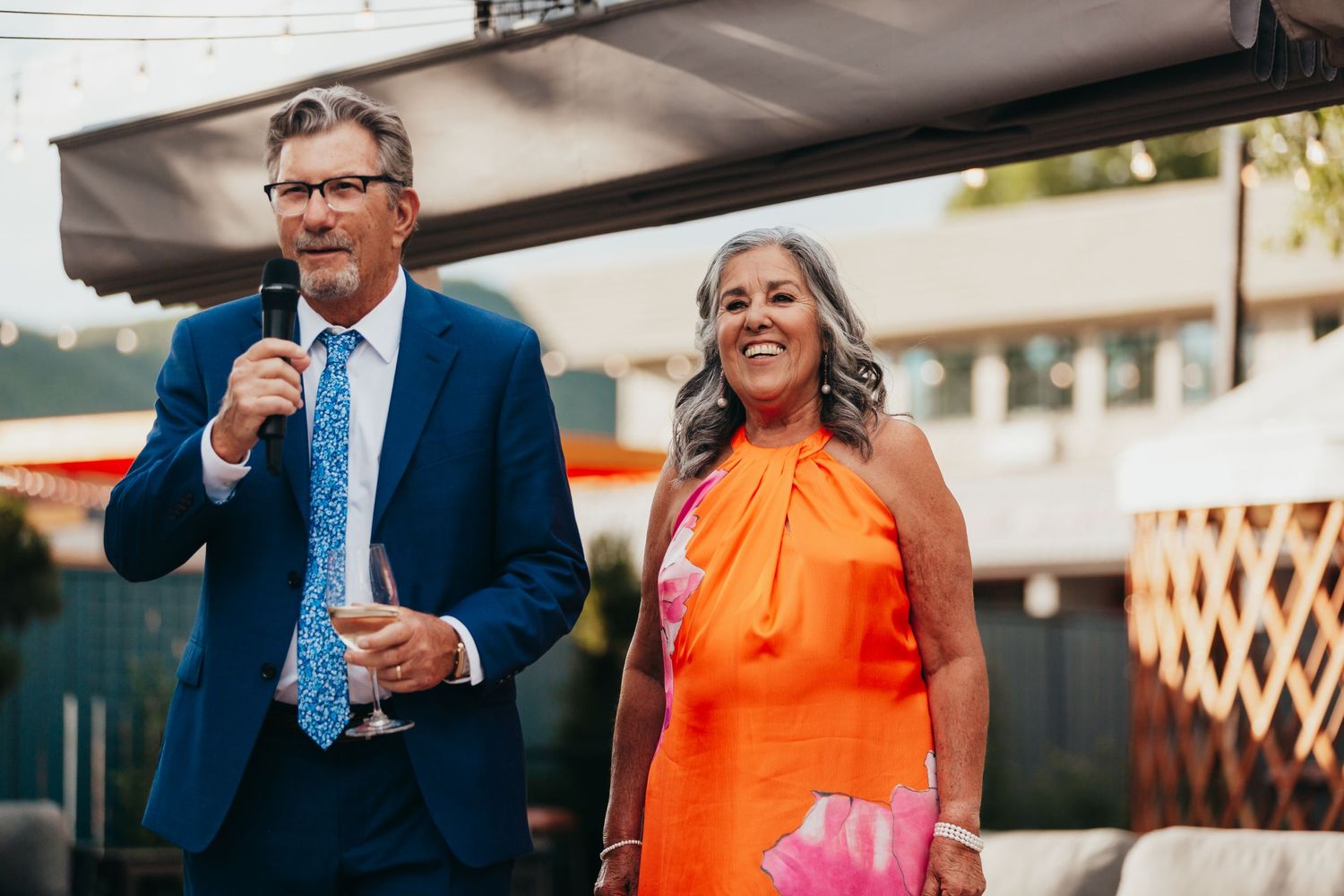 Wedding guests sharing joyful moments during outdoor reception speeches.