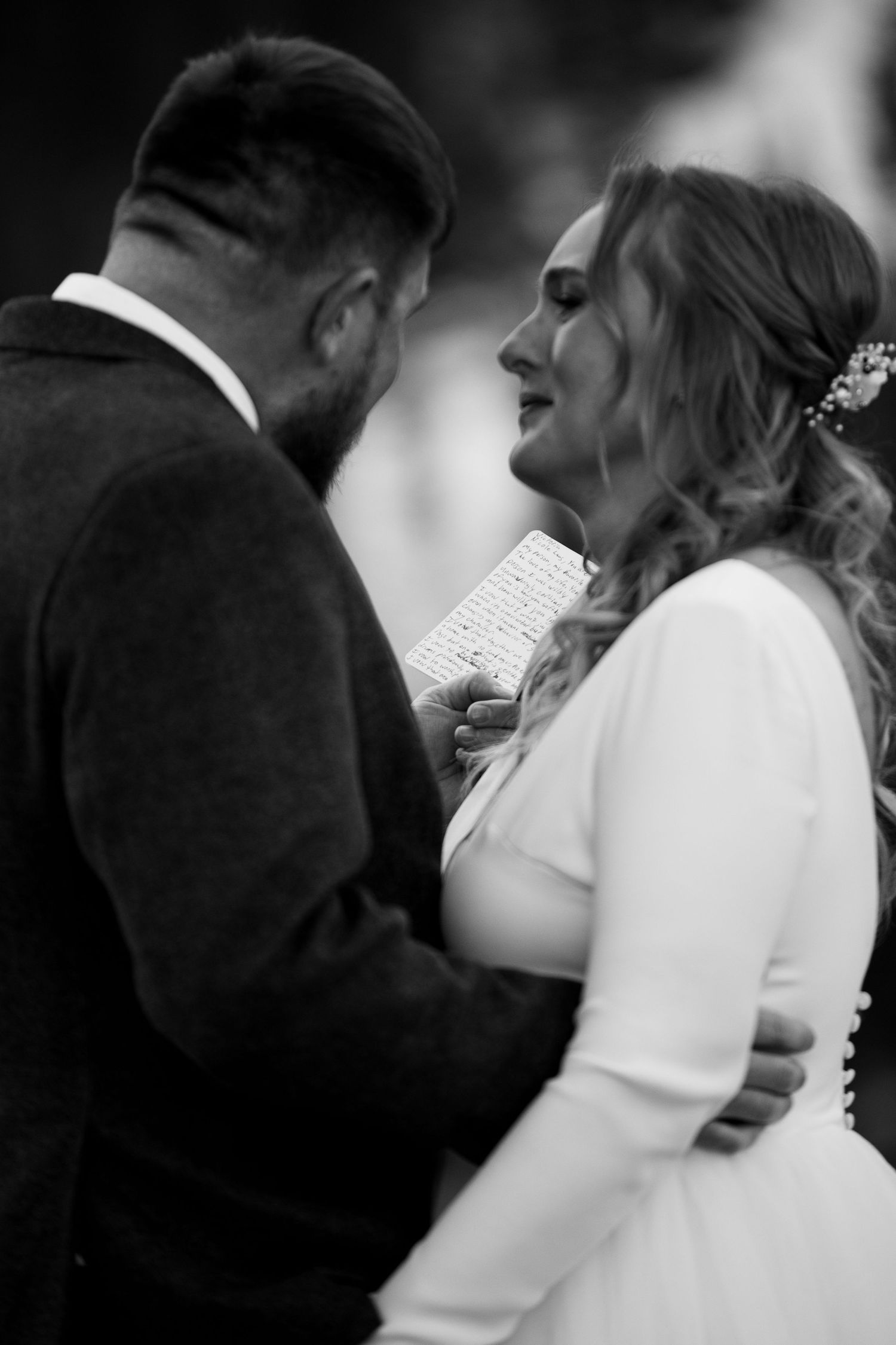 Black and white intimate moment of couple reading vows during wedding ceremony.