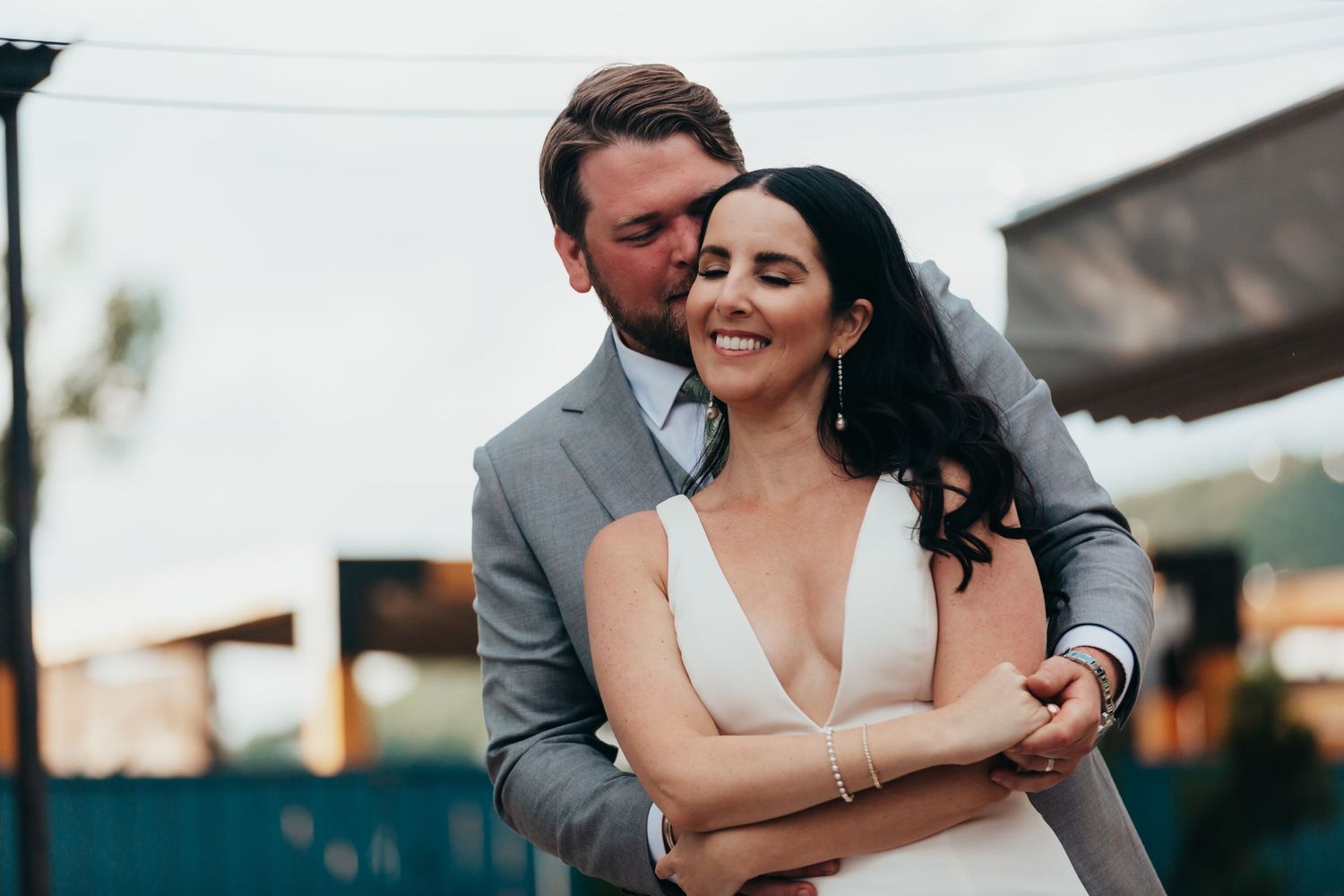 Intimate moment between bride in white dress and groom in grey suit.