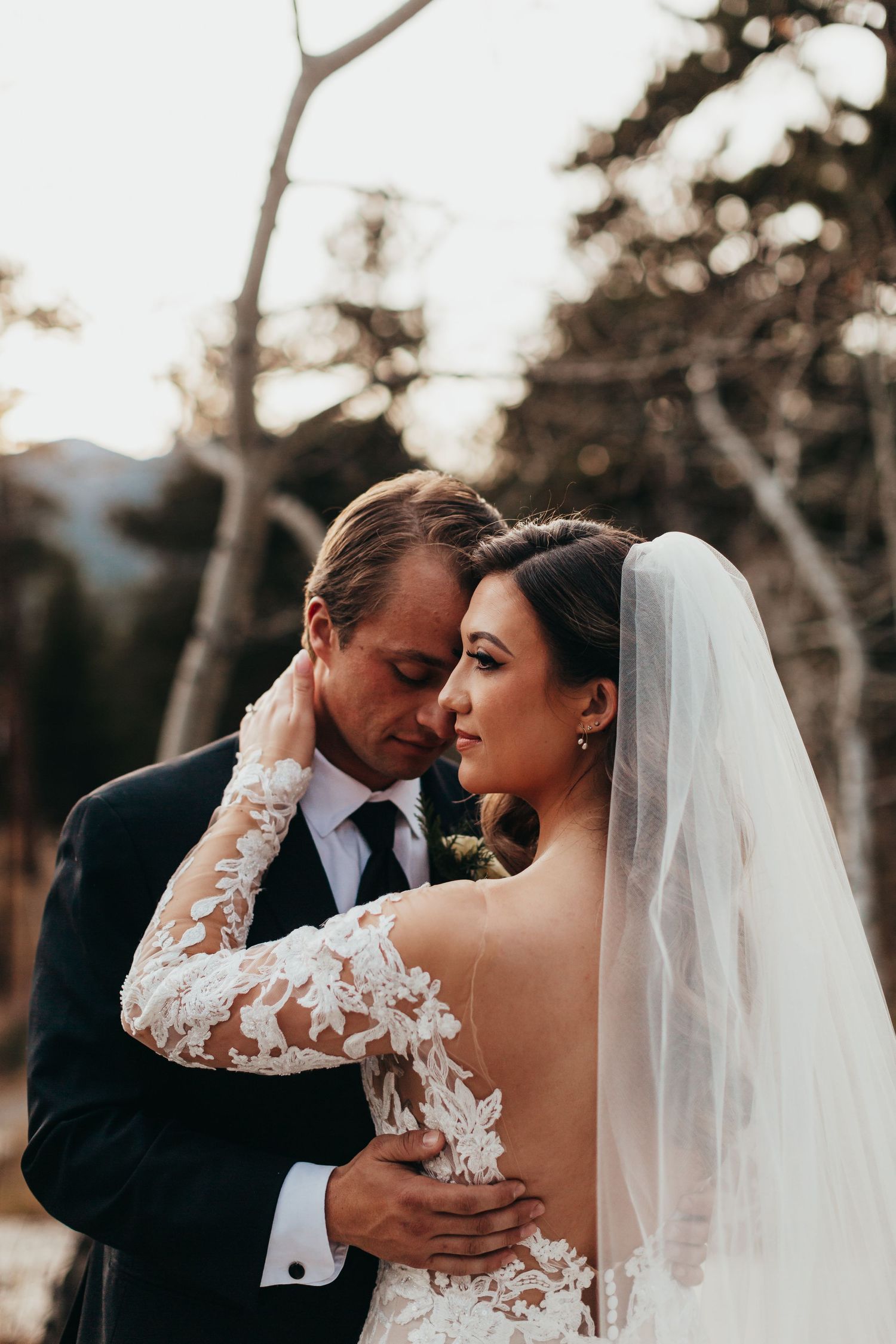 A tender wedding moment between newlyweds as the bride wears a detailed lace sleeve dress.