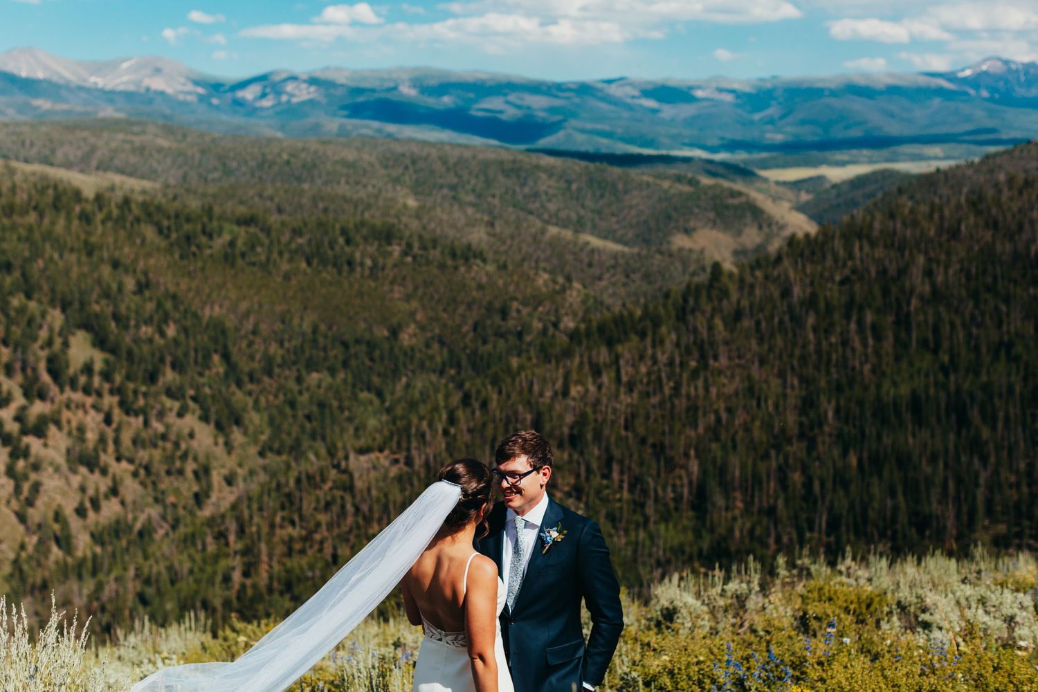 A couple embraces on a mountain overlook with sweeping valley views.