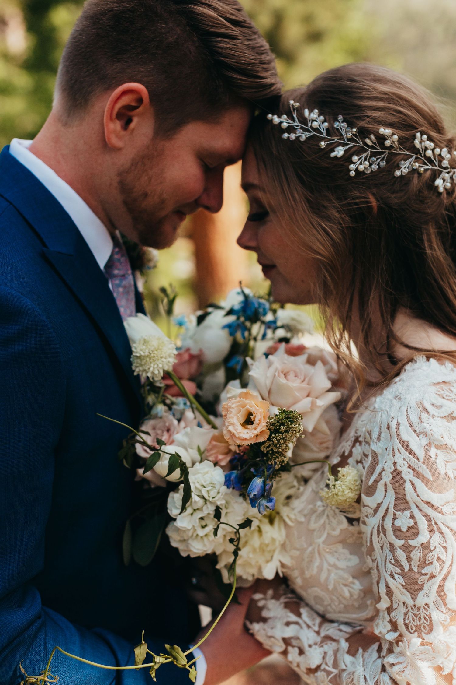 Romantic wedding portrait of a couple sharing an intimate moment with a beautiful floral bouquet and delicate bridal headpiece.