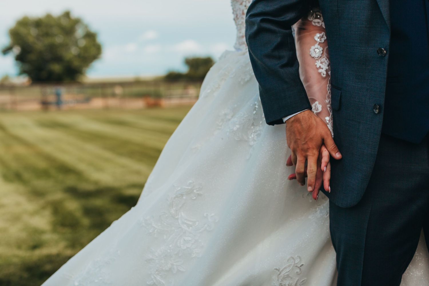 Close-up detail of a wedding dress and suit at an outdoor garden venue.
