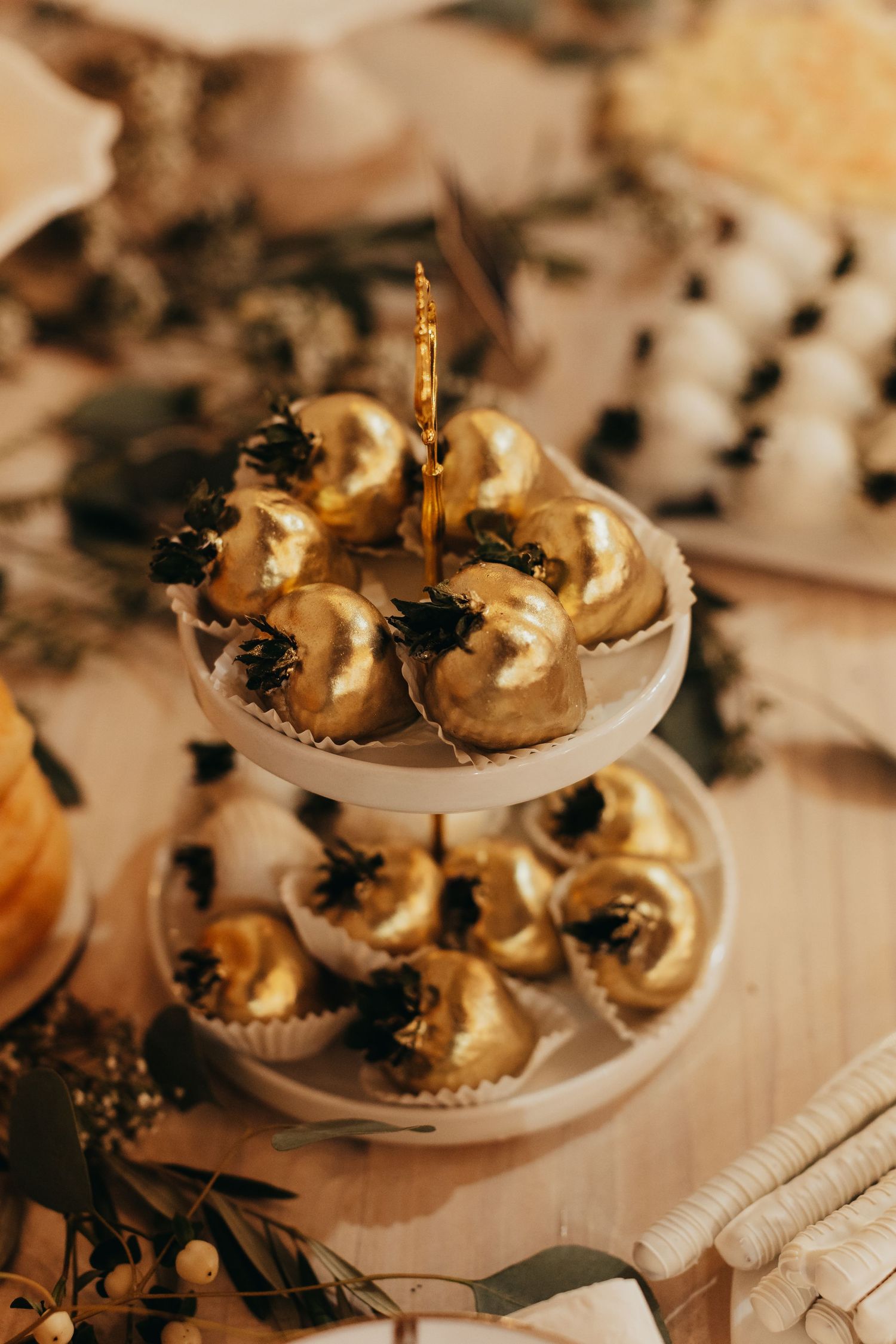 Elegant tiered dessert stand with golden frosted cupcakes decorated with black accents.
