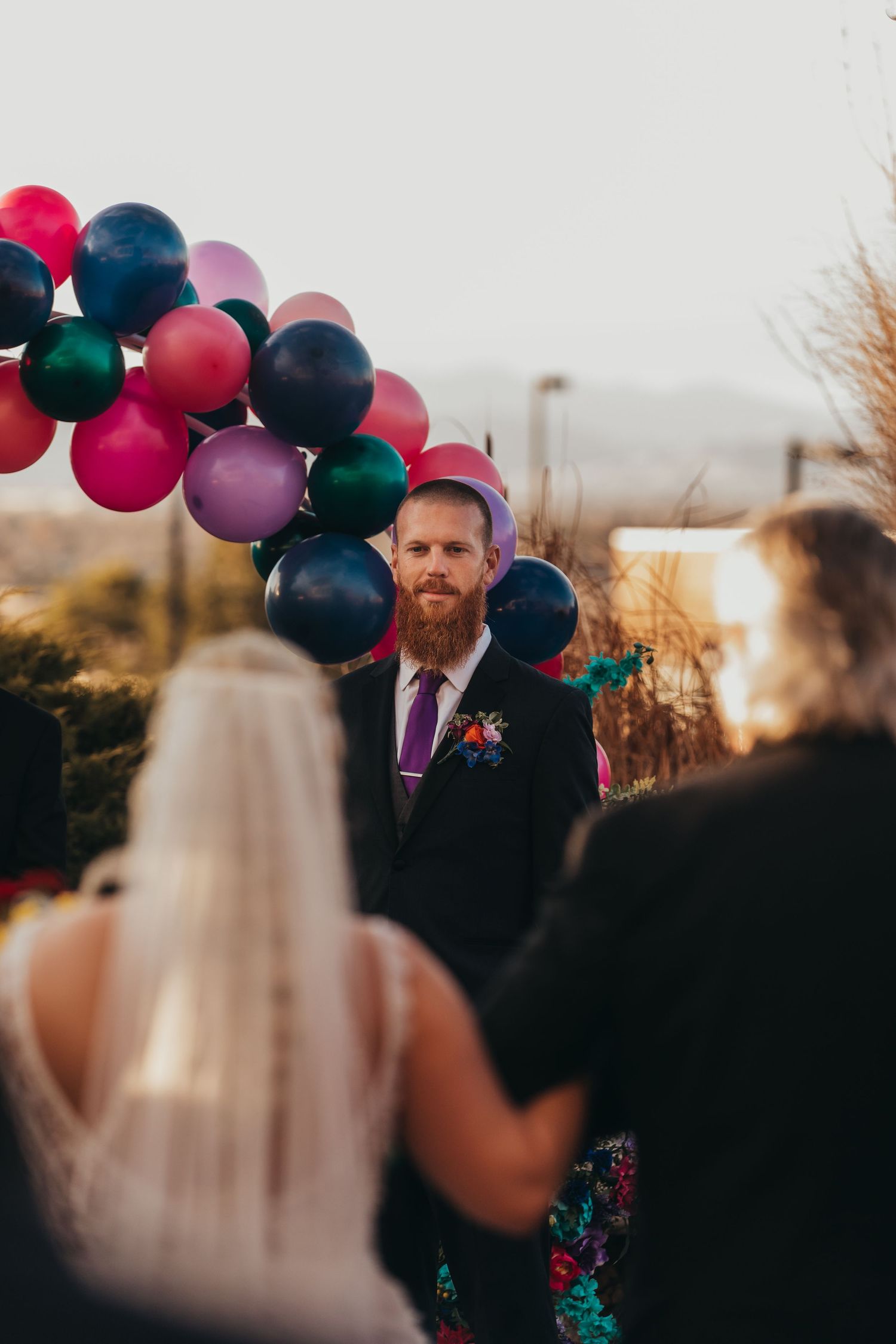 Outdoor wedding ceremony setup with colorful balloons and decorations at sunset.