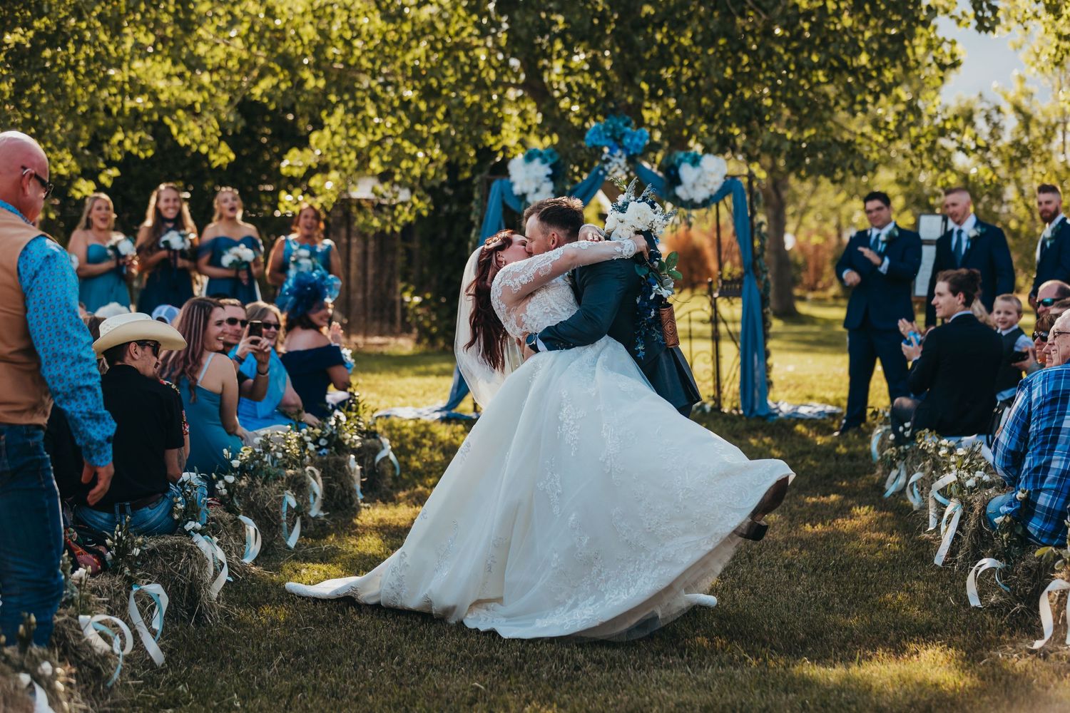 A couple shares their first dance surrounded by guests at an outdoor wedding celebration.