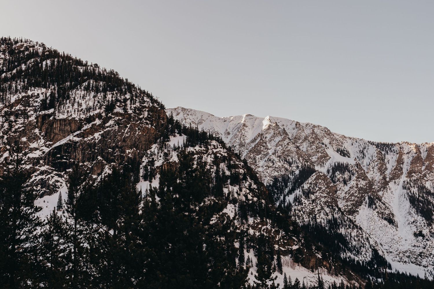 Snow-capped mountain peaks against clear sky in winter landscape.