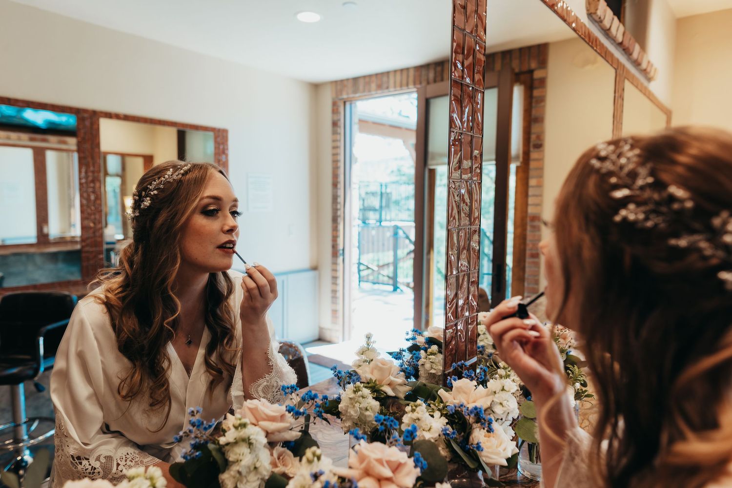 Wedding preparation scene with mirror reflection and floral decorations in getting ready room.